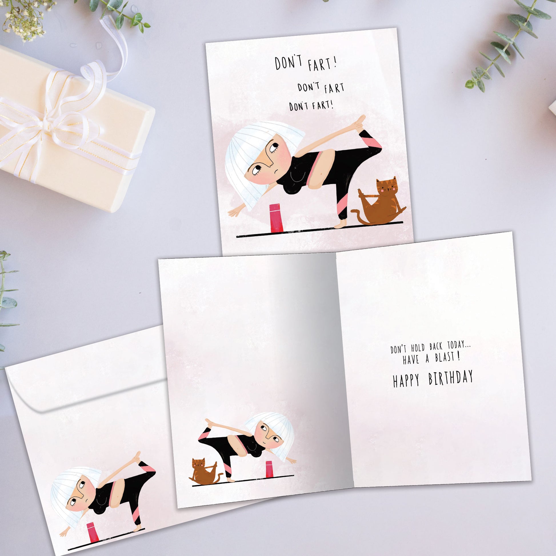 Front and inside view of a Birthday greeting card showcasing a woman and cat doing yoga and the message "Don’t fart!", with a matching envelope.