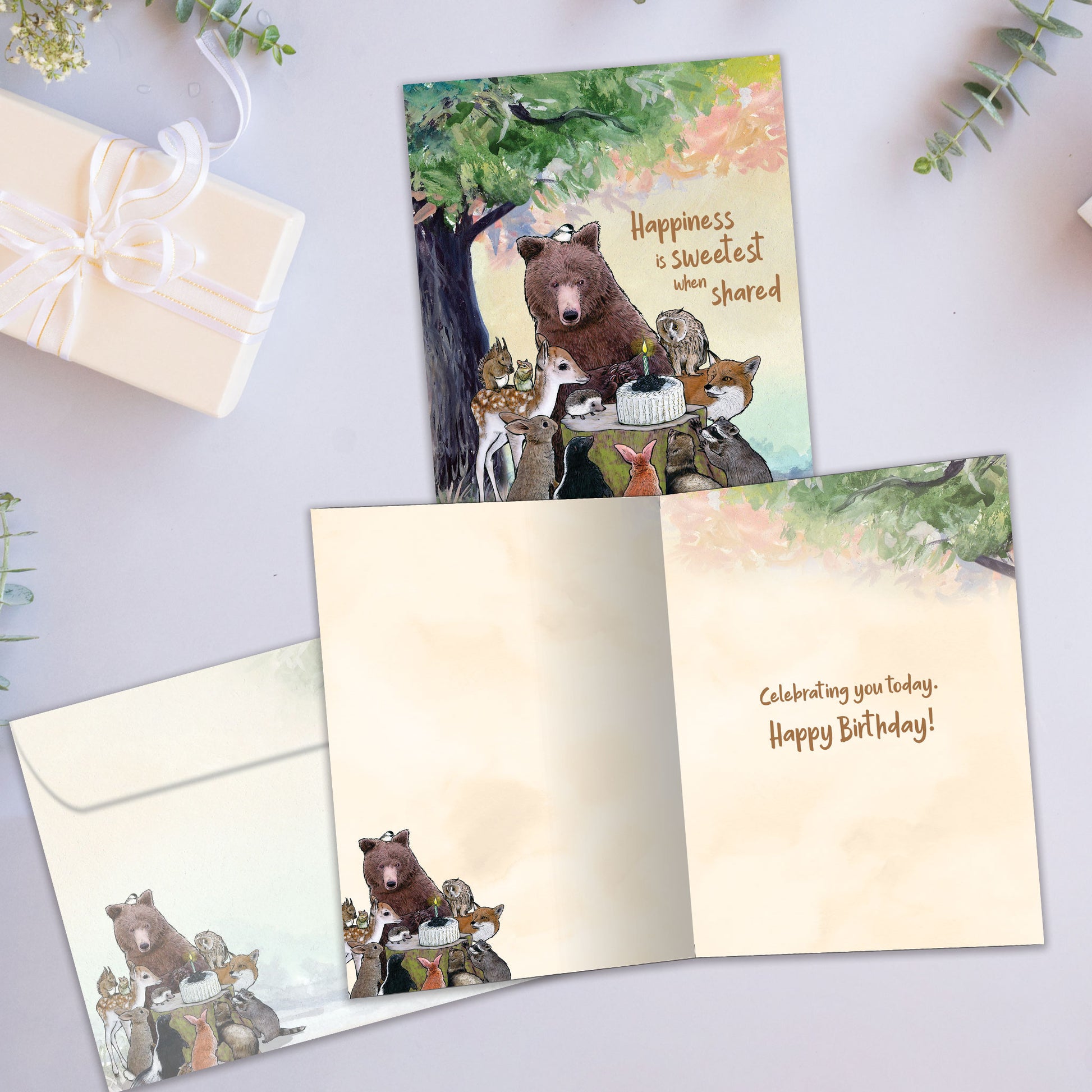 Front and inside view of a Birthday greeting card showcasing animals sitting around a birthday cake and a message, with a matching envelope.