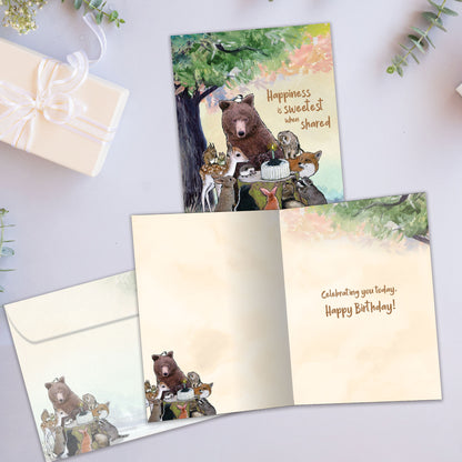 Front and inside view of a Birthday greeting card showcasing animals sitting around a birthday cake and a message, with a matching envelope.