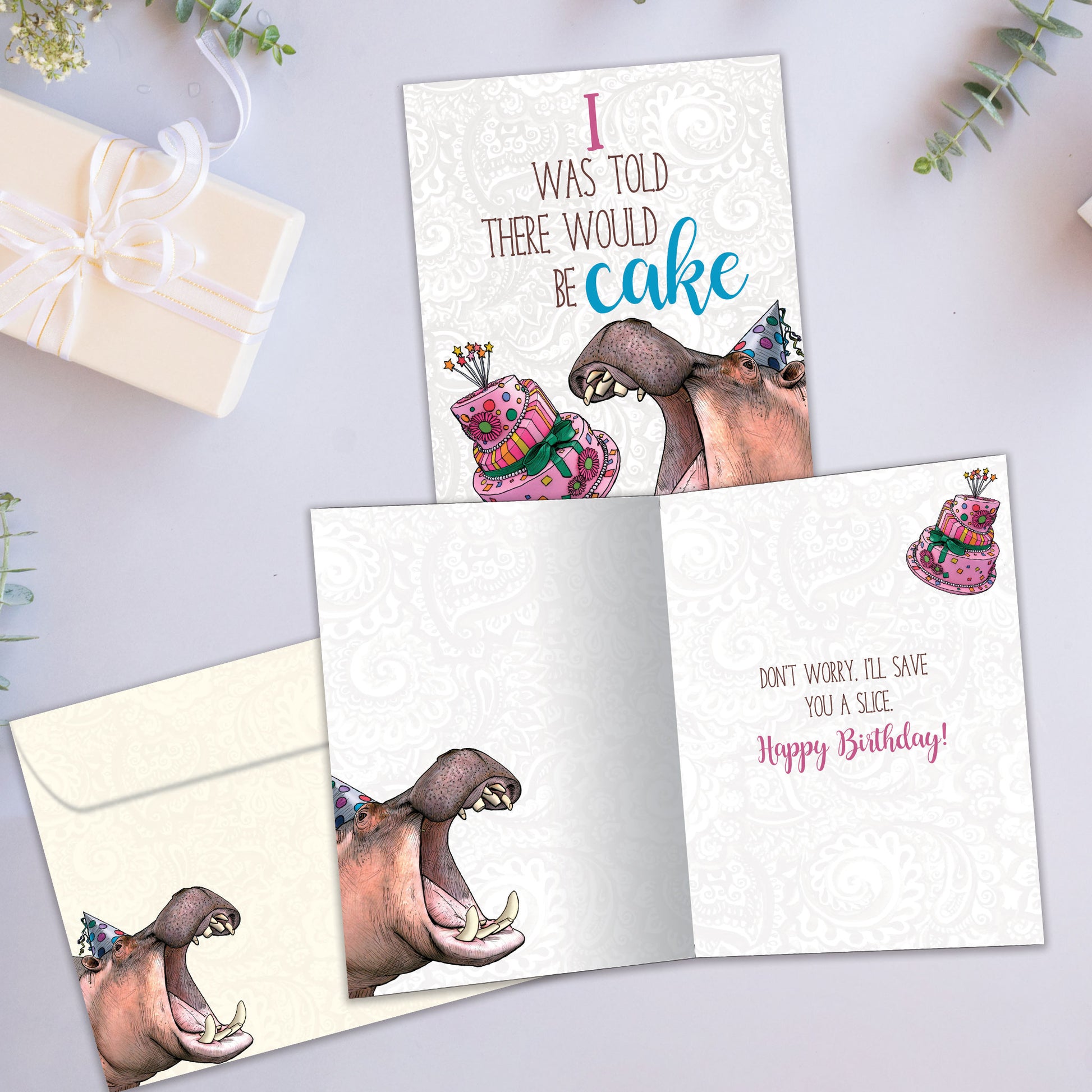 Front and inside view of a Birthday greeting card an image of a hippopotamus wearing a birthday cap about to eat cake, with a matching envelope
