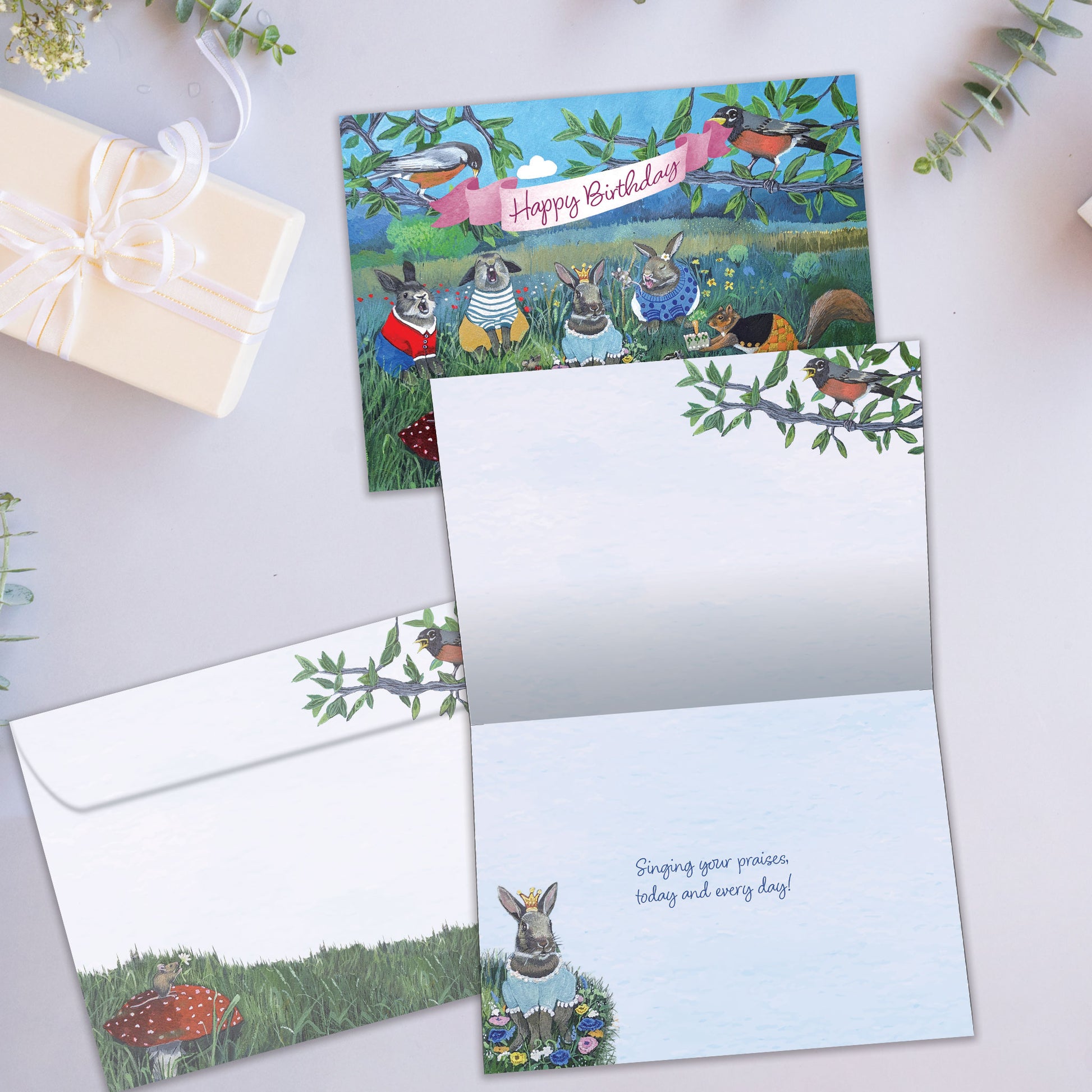 Front and inside view of a Birthday greeting card showcasing animals celebrating a birthday with the message "Happy Birthday", with a matching envelope