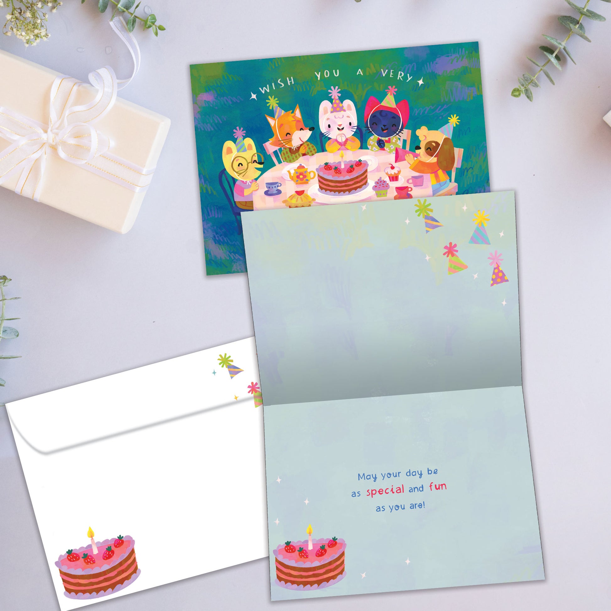 Front and inside view of a Birthday greeting card showcasing an illustration of animals sitting around a birthday cake, with a matching envelope.