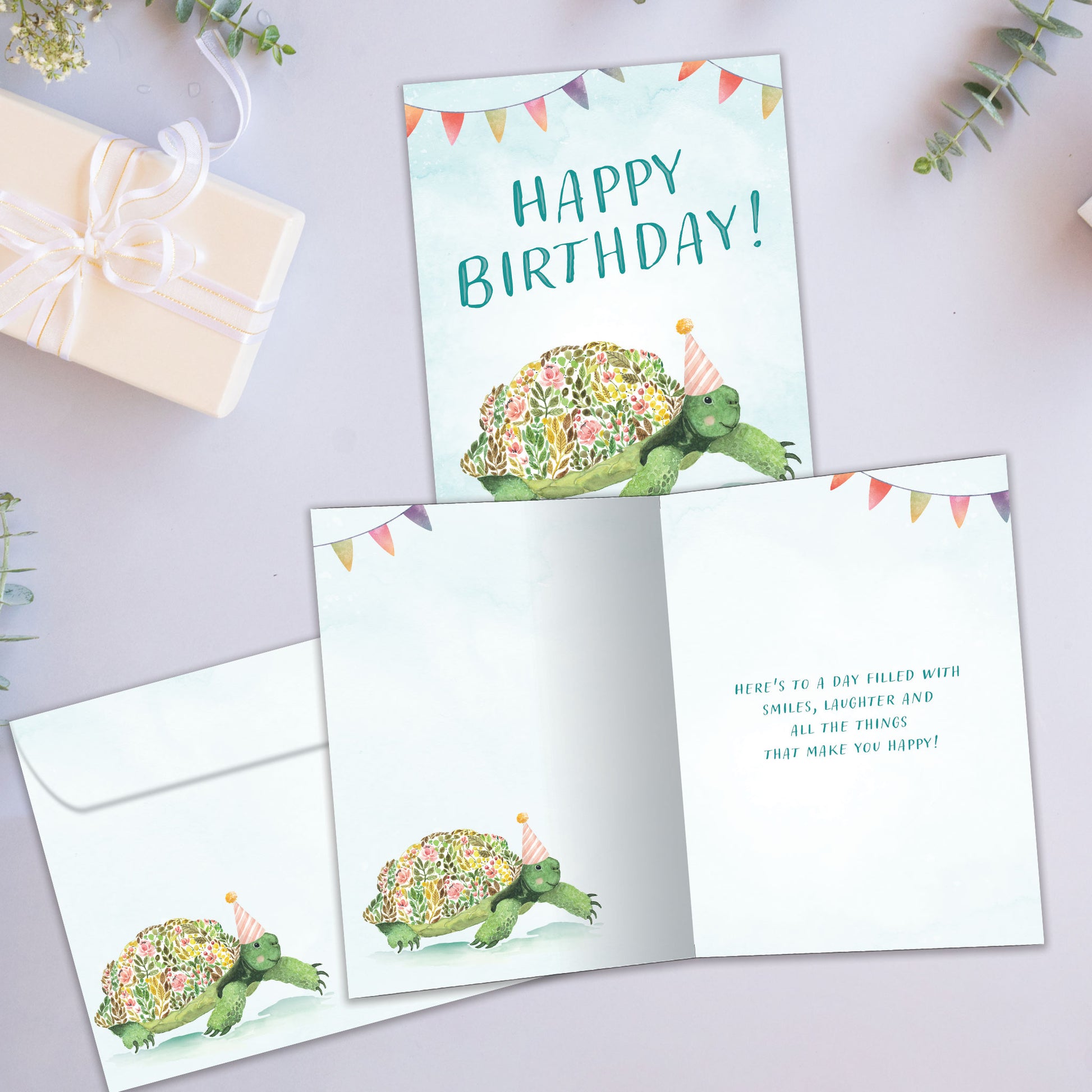 Front and inside view of a Birthday greeting card showcasing a flowery turtle with the message "Happy Birthday", with a matching envelope.