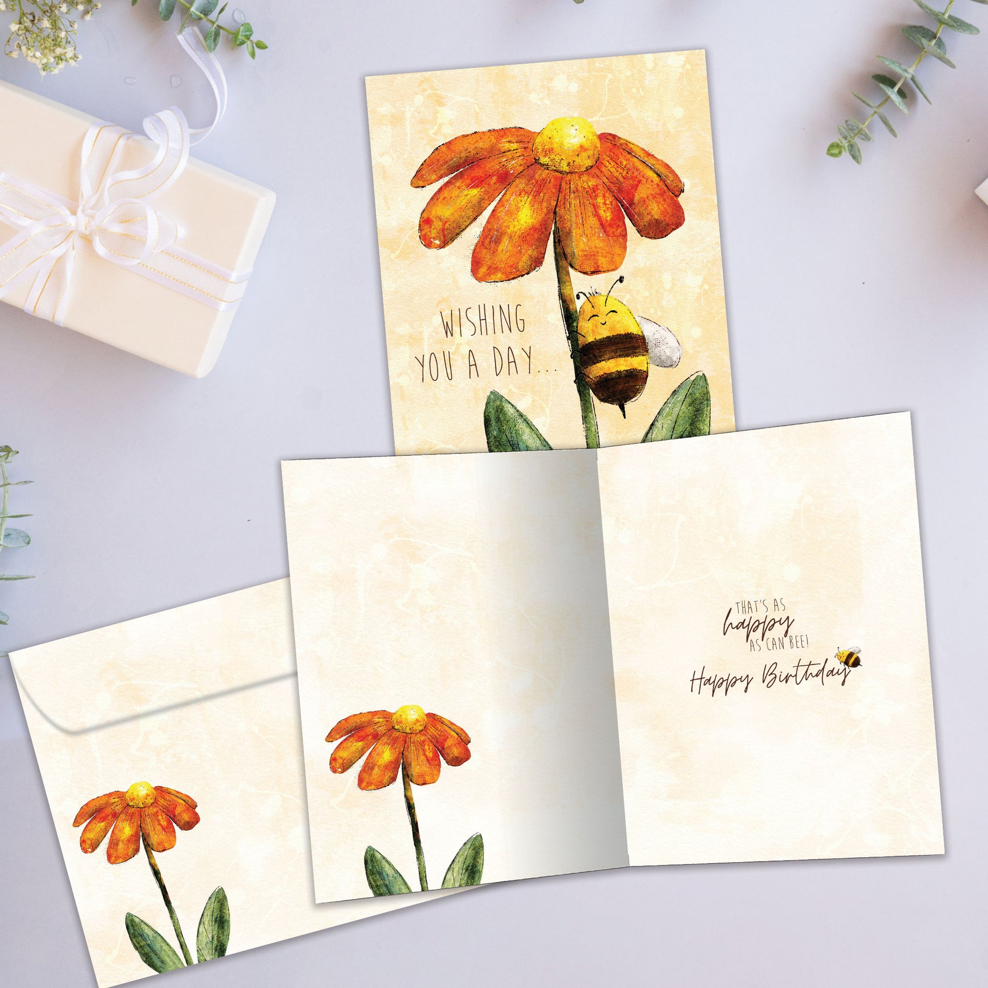 Front and inside view of a Birthday greeting card showcasing a smiling honey bee on a colourful flower, with a matching envelope