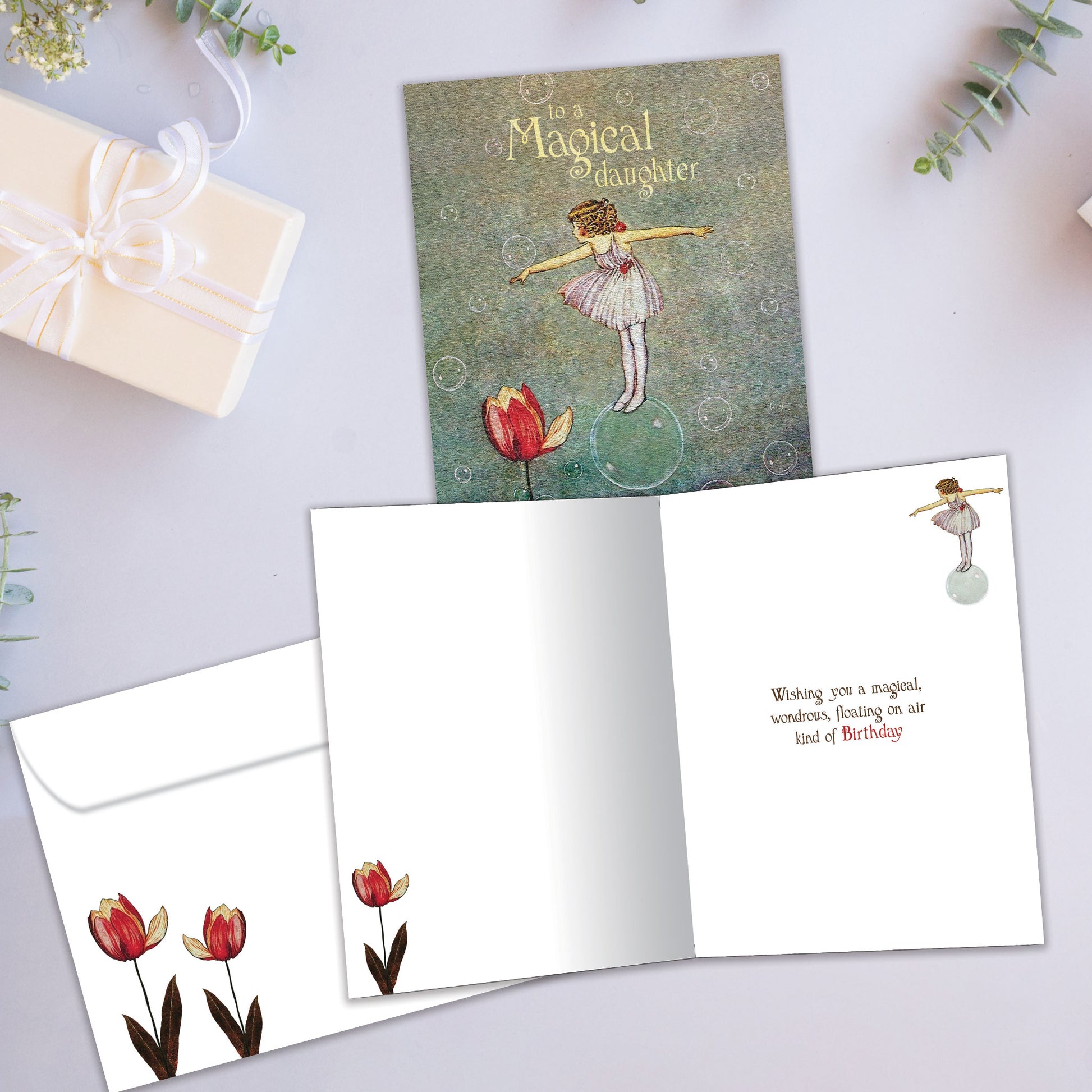 Front and inside view of a Birthday greeting card with a girl floating on a bubble and the message "to a magical daughter", with a matching envelope.