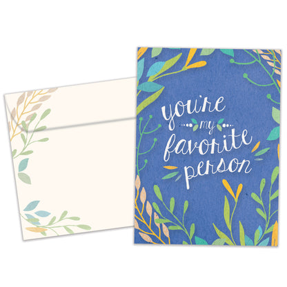 Front view of an All Occasion greeting card and matching envelope featuring the message 'You're my favorite person' surrounded by soft-coloured foliage on a blue background.