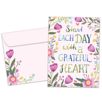 Front view of an All Occasion greeting card and matching envelope with the message 'Start each day with a grateful heart' surrounded by delicate flowers.