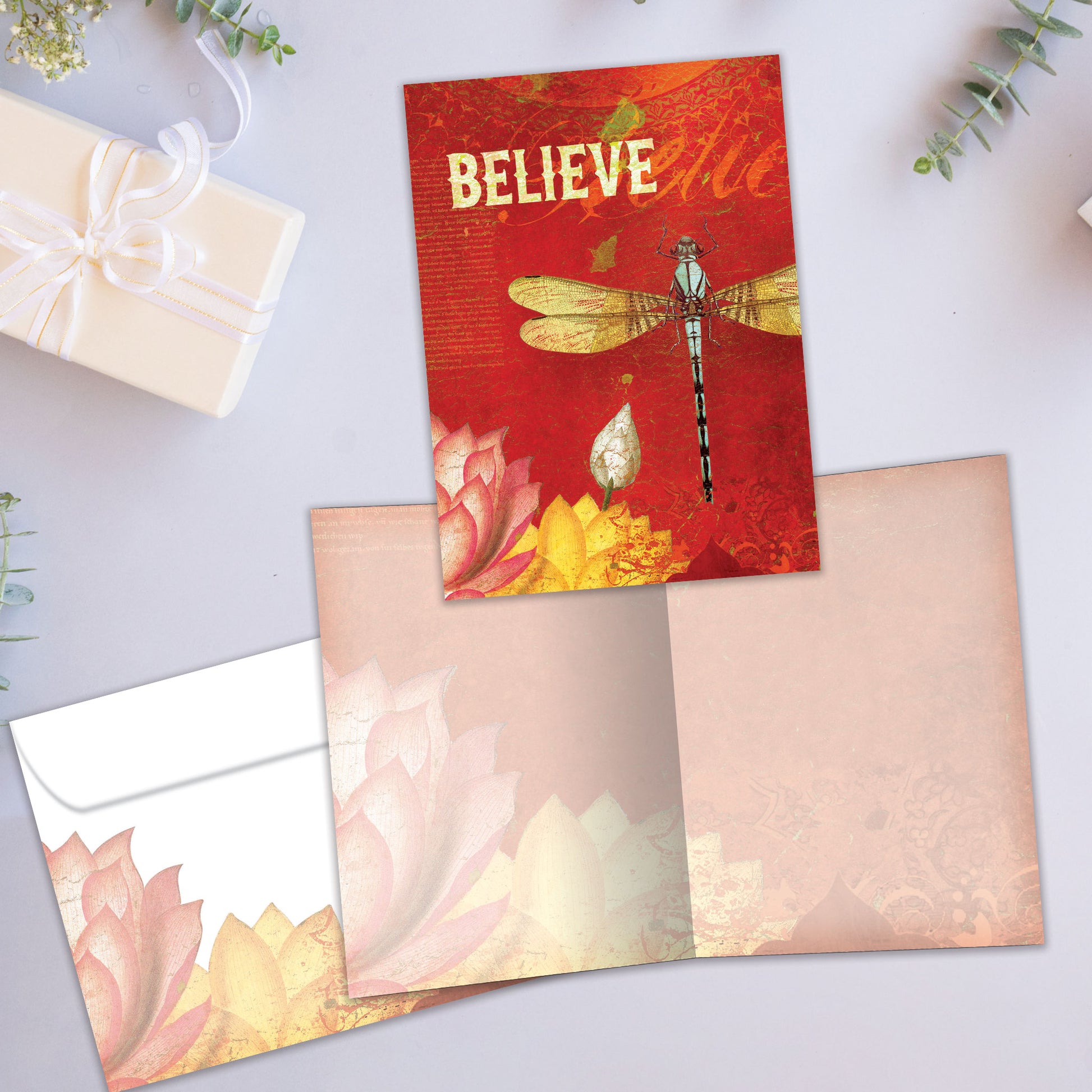 Front and inside view of an All Occasion greeting card showcasing a dragonfly and flowers illustration, the word 'Believe,' and a matching envelope.