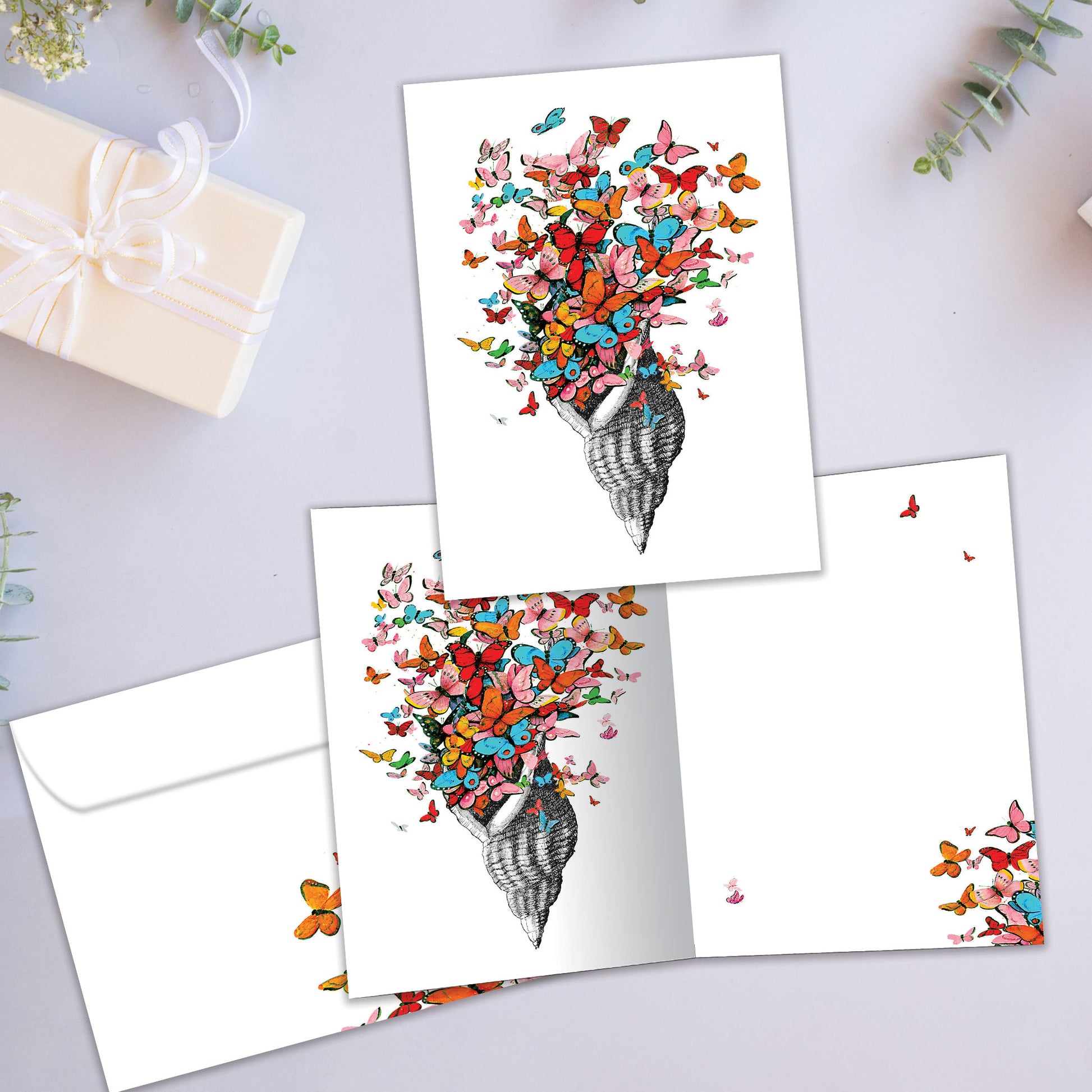 Front and inside view of an All Occasion greeting card showcasing a shell with butterflies in a joyful design, with a matching envelope.
