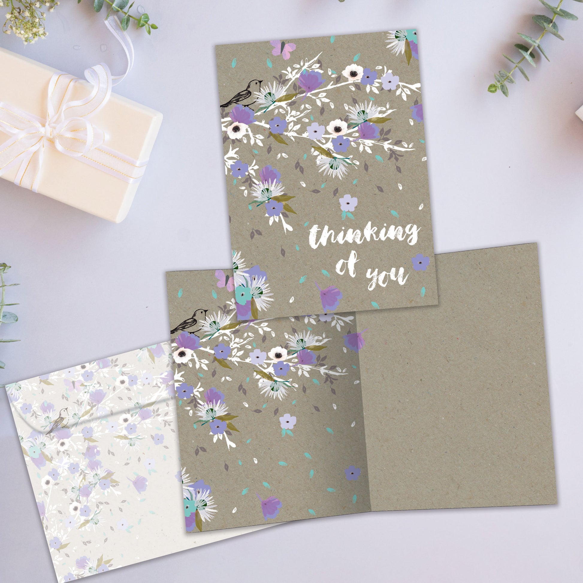 Front and inside view of an All Occasion greeting card showcasing purple flowers with 'Thinking of You' text, with a matching envelope.