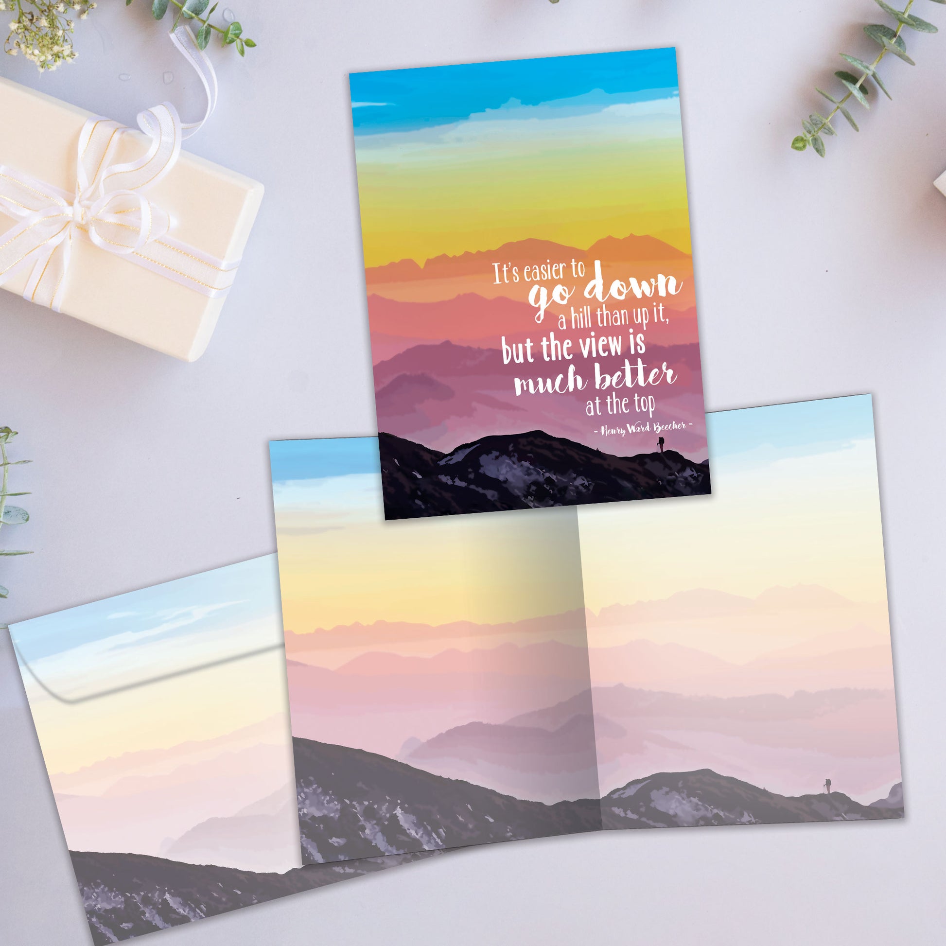 Front and inside view of an All Occasion greeting card showcasing a person climbing a mountain with an inspirational message about the view from the top, with a matching envelope.
