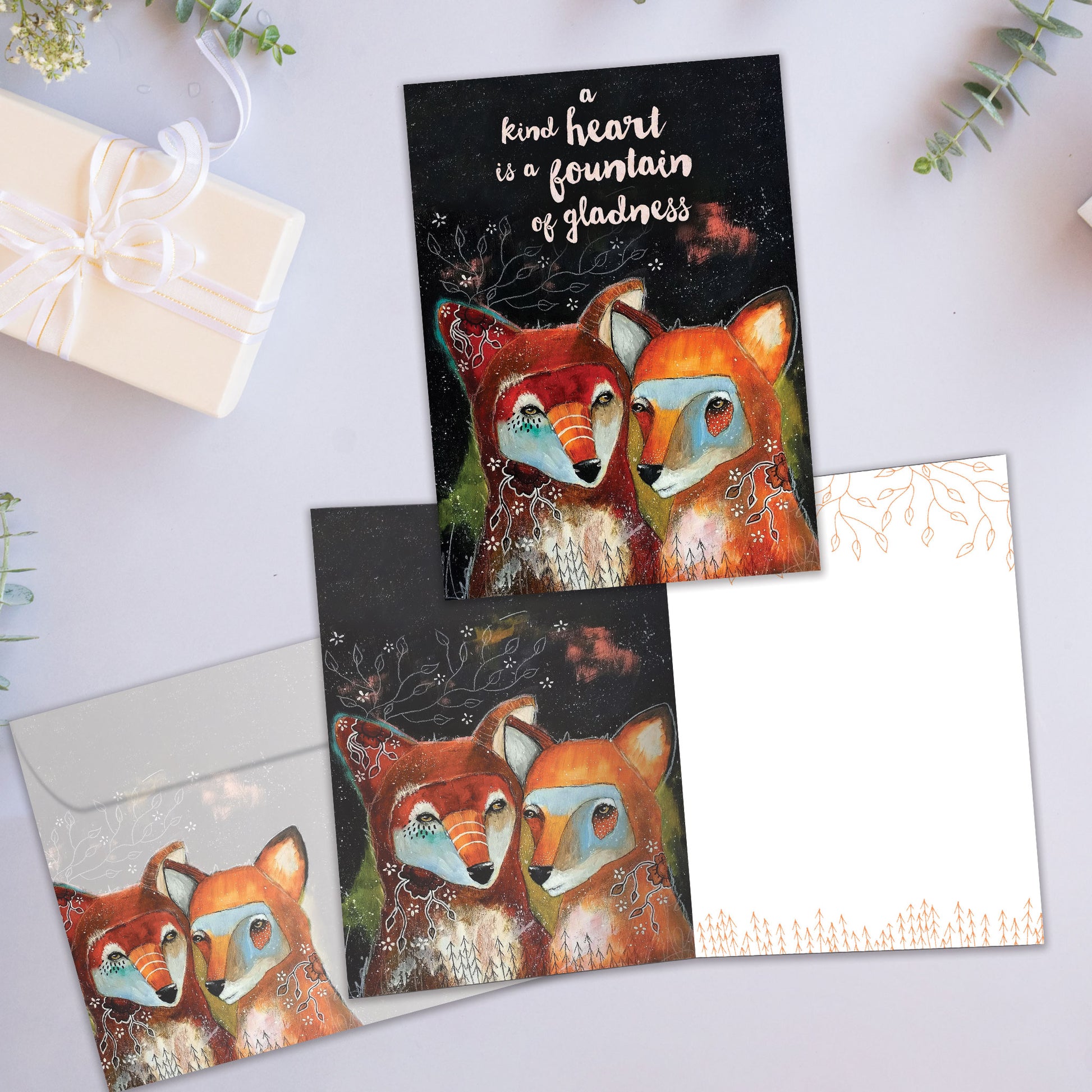 Front and inside view of an All Occasion greeting card showcasing two foxes and a message about a kind heart, with a matching envelope.