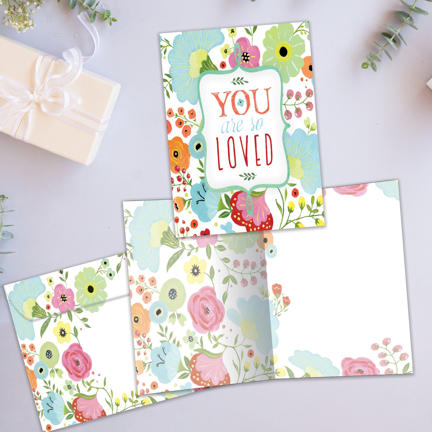 Front and inside view of an All Occasion greeting card showcasing the message 'You are so loved' surrounded by soft-coloured flowers, with a matching envelope.