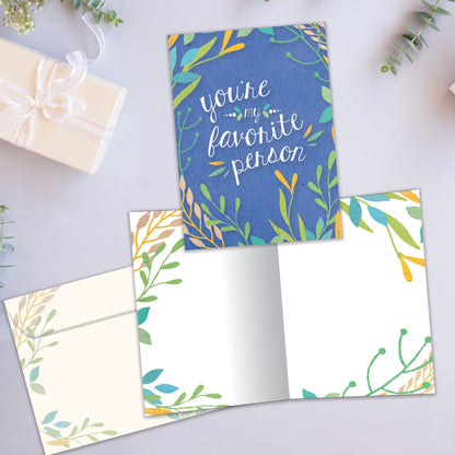 Front and inside view of an All Occasion greeting card showcasing the message 'You're my favorite person' surrounded by soft-coloured foliage on a blue background, with a matching envelope.