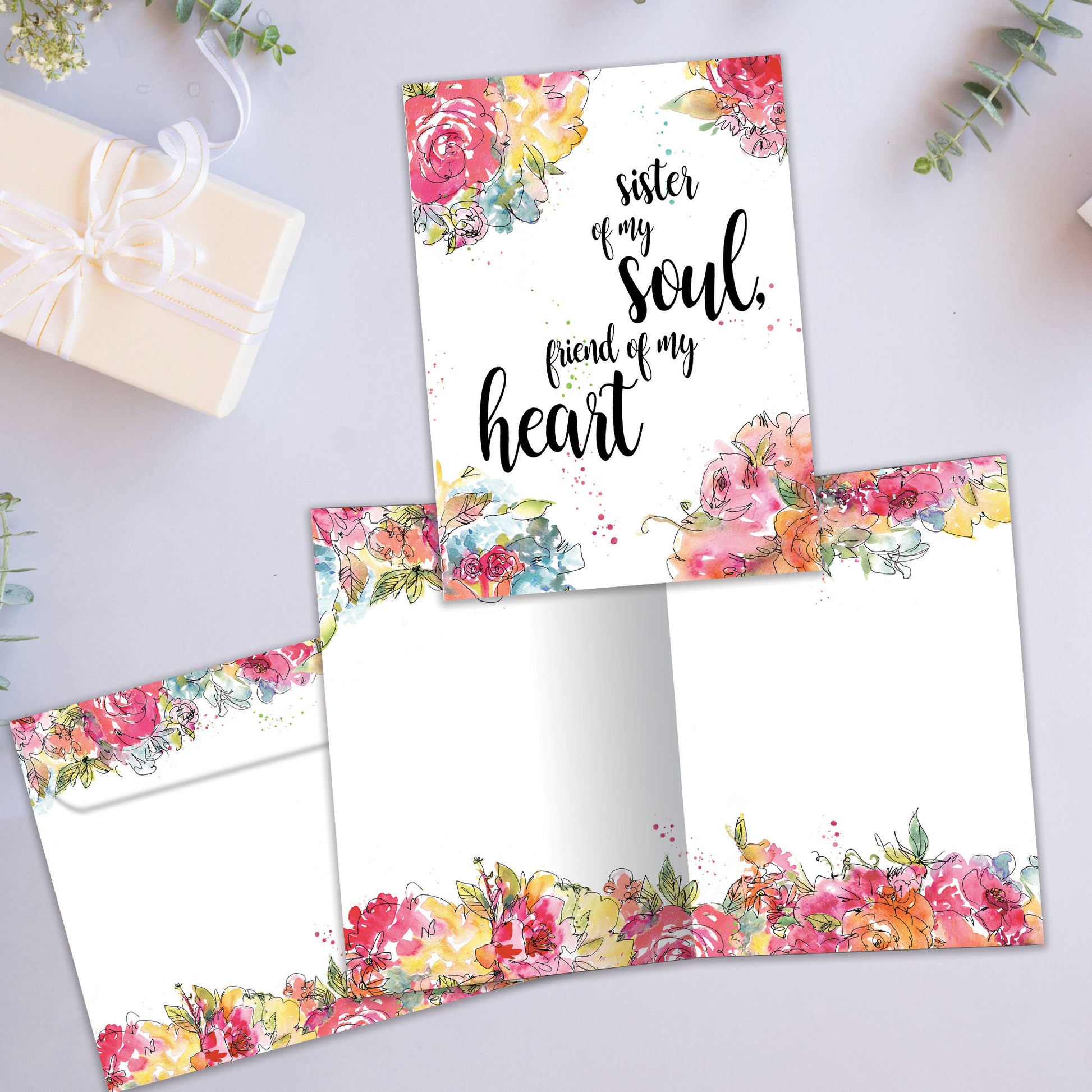 Front and inside view of an All Occasion greeting card showcasing the message 'Sister of my soul, friend of my heart' surrounded by watercolour flowers, with a matching envelope.