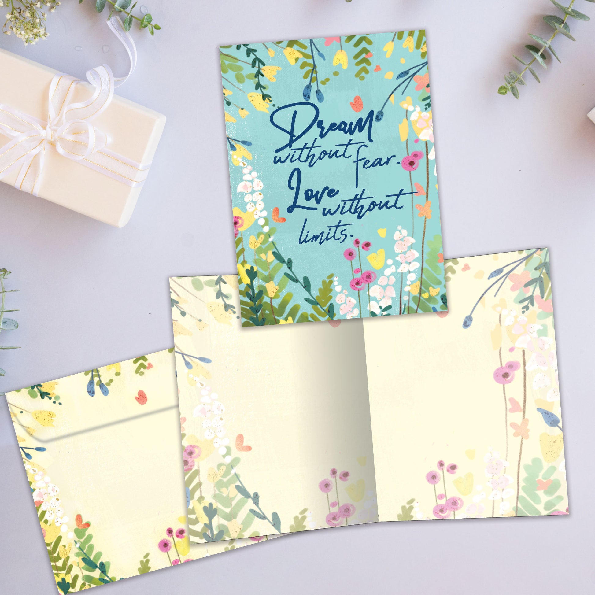 Front and inside view of an All Occasion greeting card showcasing the message 'Dream without fear. Love without limits.' on a light blue background with colourful flowers, with a matching envelope.
