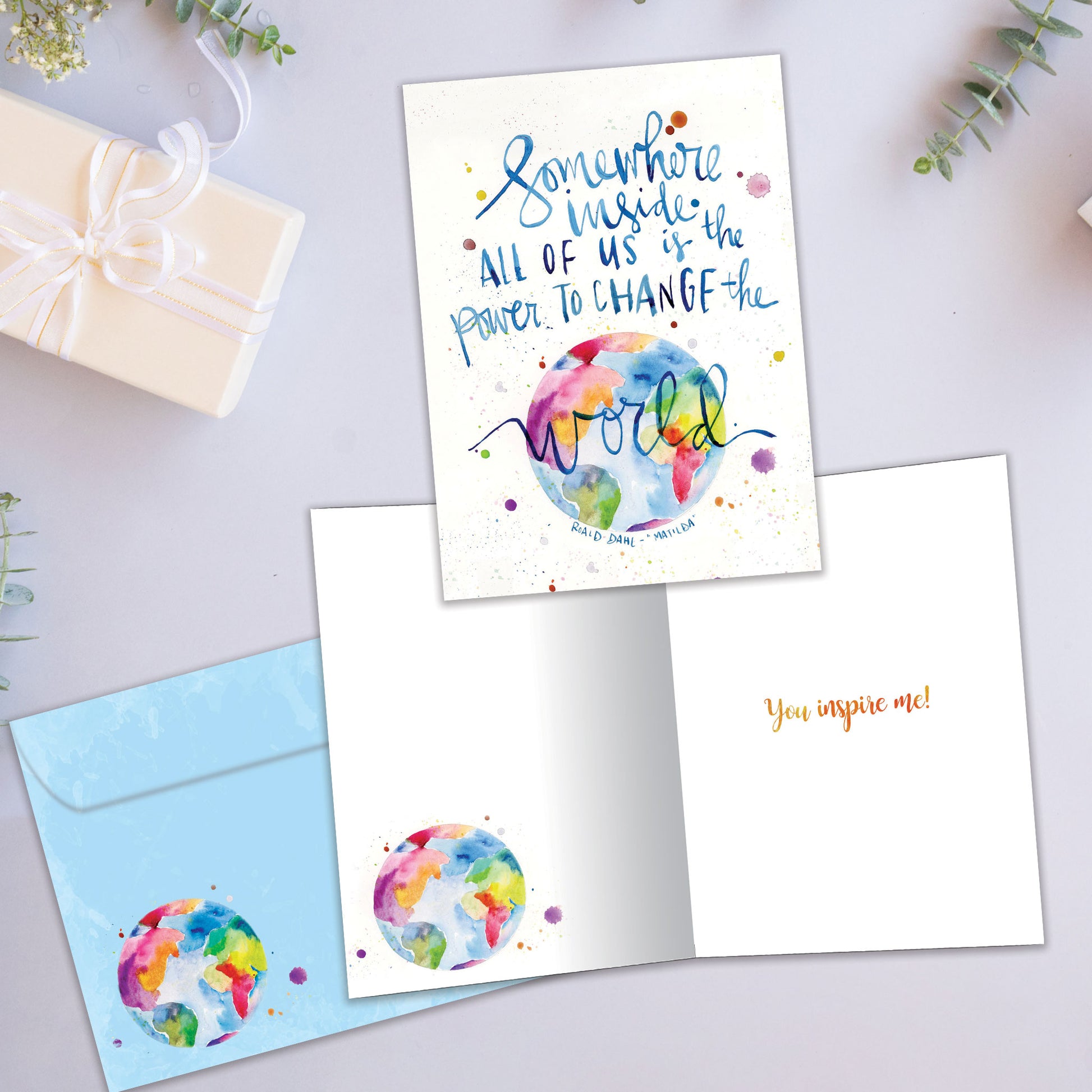 Front and inside view of an All Occasion greeting card featuring a colourful world illustration with an uplifting message, plus a matching envelope.