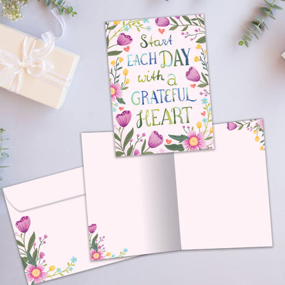 Front and inside view of an All Occasion greeting card featuring the message 'Start each day with a grateful heart' surrounded by delicate flowers, plus a matching envelope.