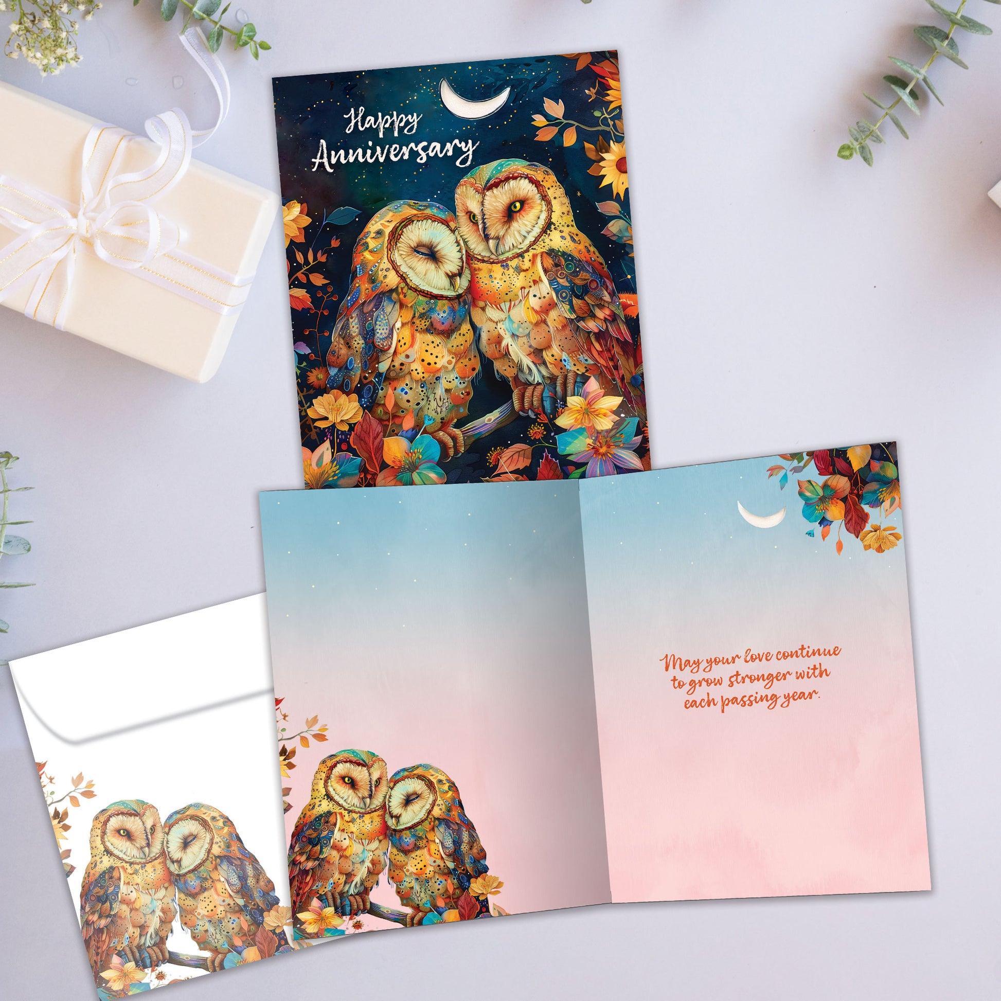 Front and inside view of an Anniversary greeting card showcasing an owl couple nestled in a colourful tree beneath the moon, with a matching envelope.