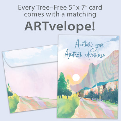 Front view of a Birthday greeting card featuring an illustration of a country road with the message "Another year, Another adventure," with matching envelope artwork.