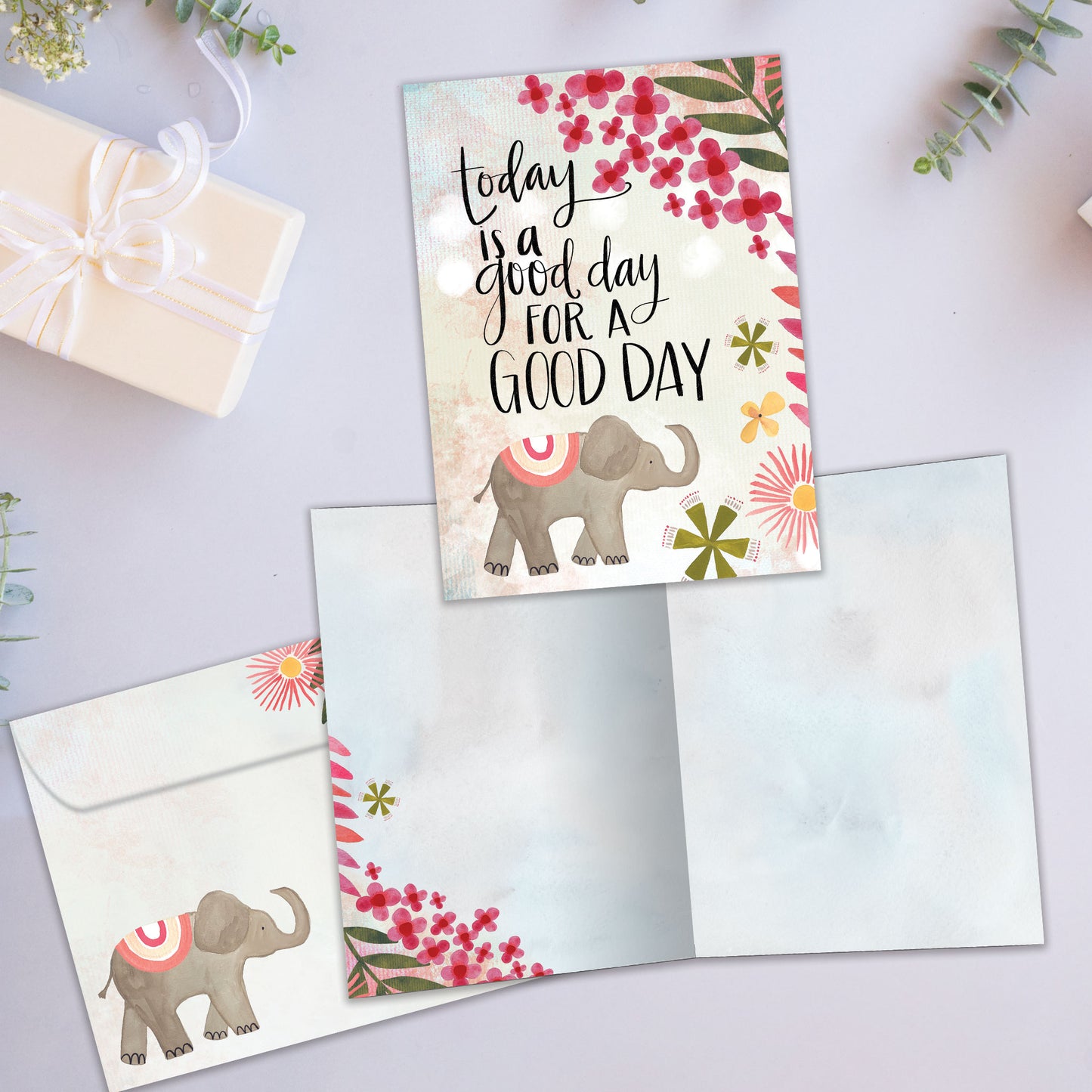 Front and inside view of an All Occasion greeting card featuring a lively elephant and flower illustration with a good day message, plus matching envelope.