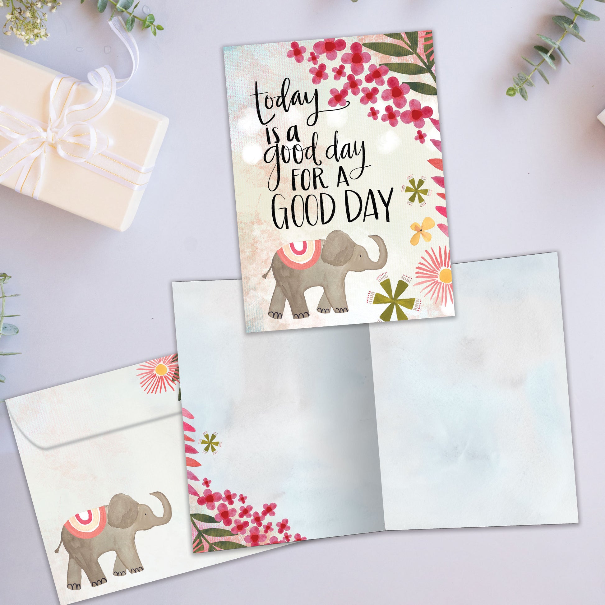 Front and inside view of an All Occasion greeting card featuring a lively elephant and flower illustration with a good day message, plus matching envelope.