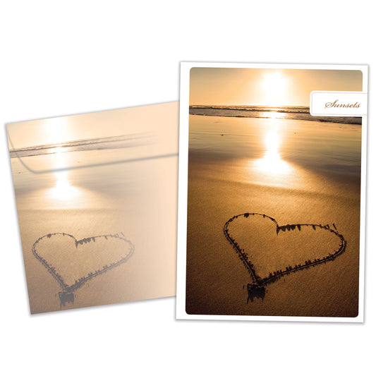 Front view of an Anniversary greeting card and matching envelope featuring a photo of a sunset with a heart drawn in the sand.