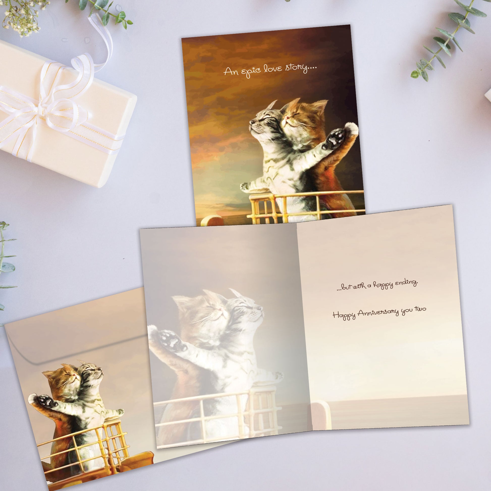 Front and inside view of an Anniversary greeting card showcasing two cats on the bow of a ship in a Titanic-inspired embrace, with a matching envelope.
