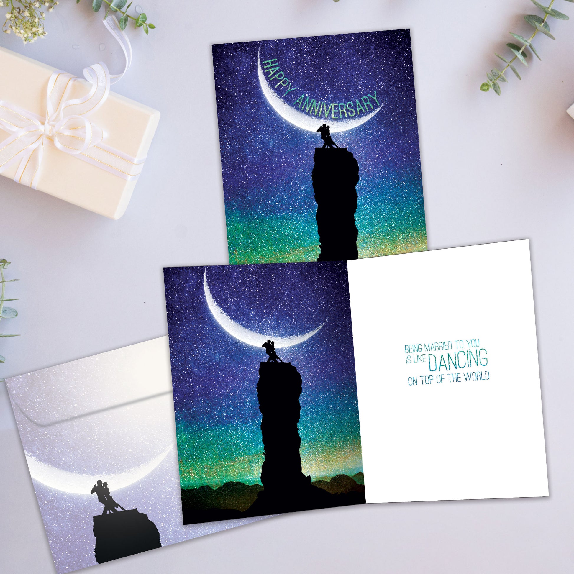 Front and inside view of an Anniversary greeting card showcasing a couple dancing in the moonlight with the words "Happy Anniversary," with a matching envelope.