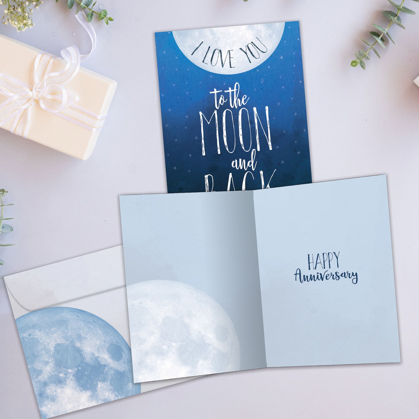 Front and inside view of an Anniversary greeting card showcasing the message "I love you to the moon and back" with a moon illustration on a dark blue sky, with a matching envelope.
