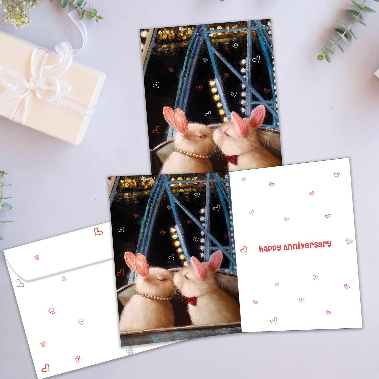 Front and inside view of an Anniversary greeting card showcasing two bunnies kissing, with a matching envelope.