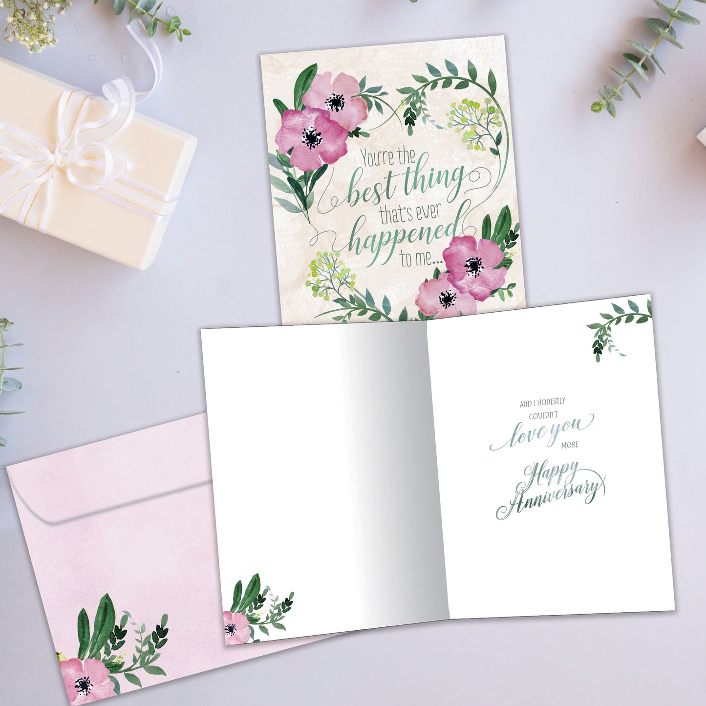 Front and inside view of an Anniversary greeting card showcasing a soft pink and green floral design with a loving message, with a matching envelope.