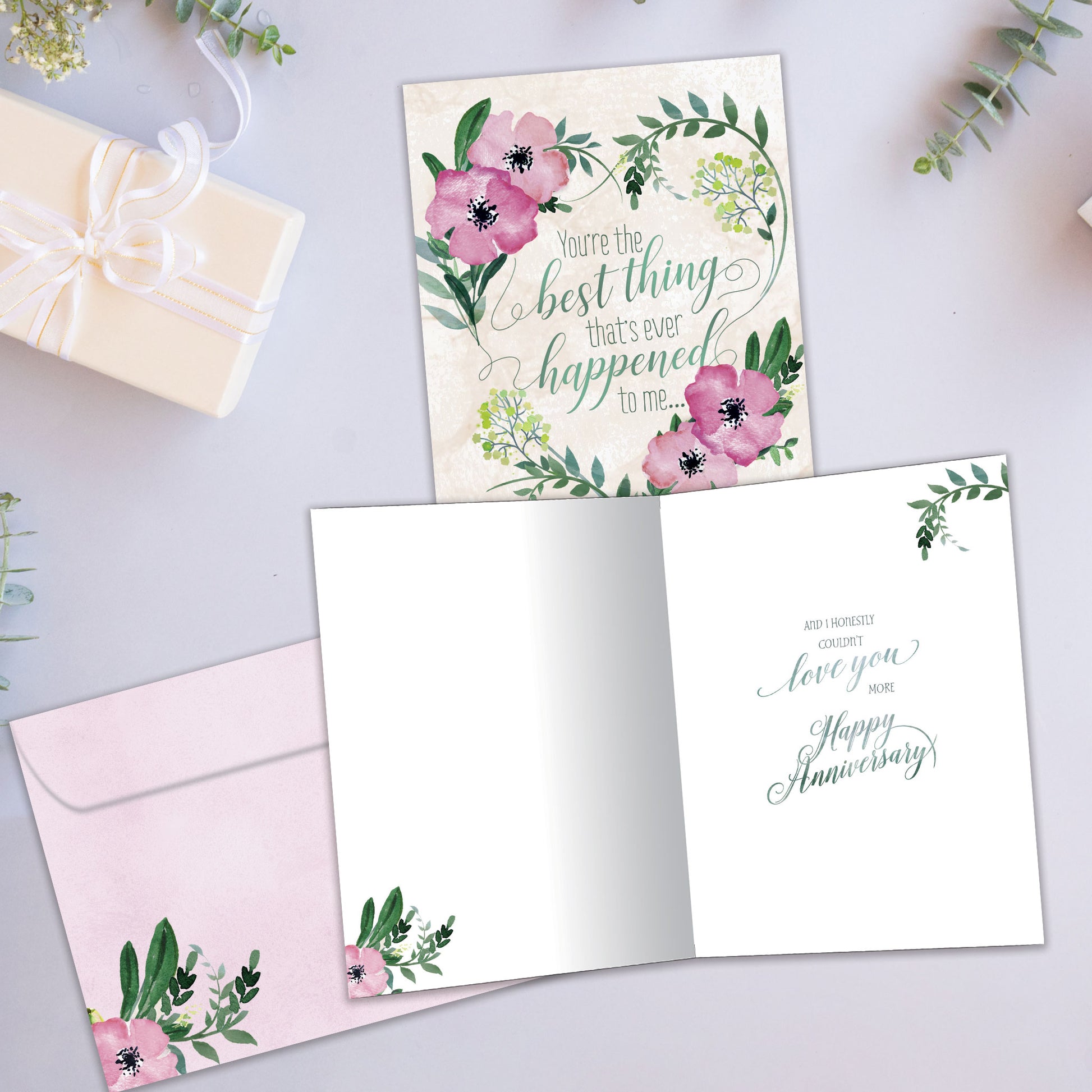 Front and inside view of an Anniversary greeting card showcasing a soft pink and green floral design with a loving message, with a matching envelope.