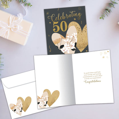 Front and inside view of an Anniversary greeting card showcasing "Celebrating 50 years" in gold on a dark background with two hearts, with a matching envelope.