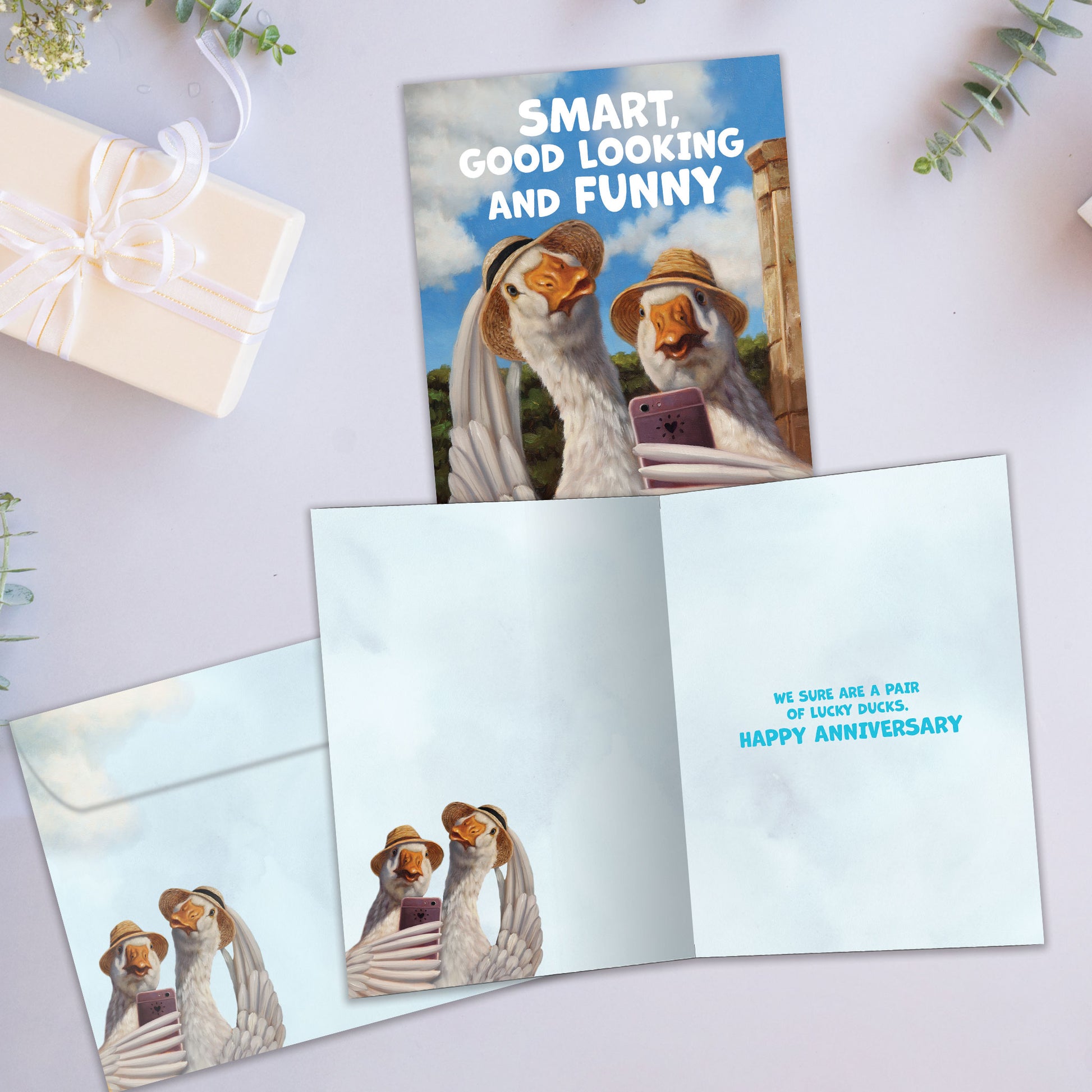Front and inside view of an Anniversary greeting card showcasing a duck couple taking a selfie, with a matching envelope.