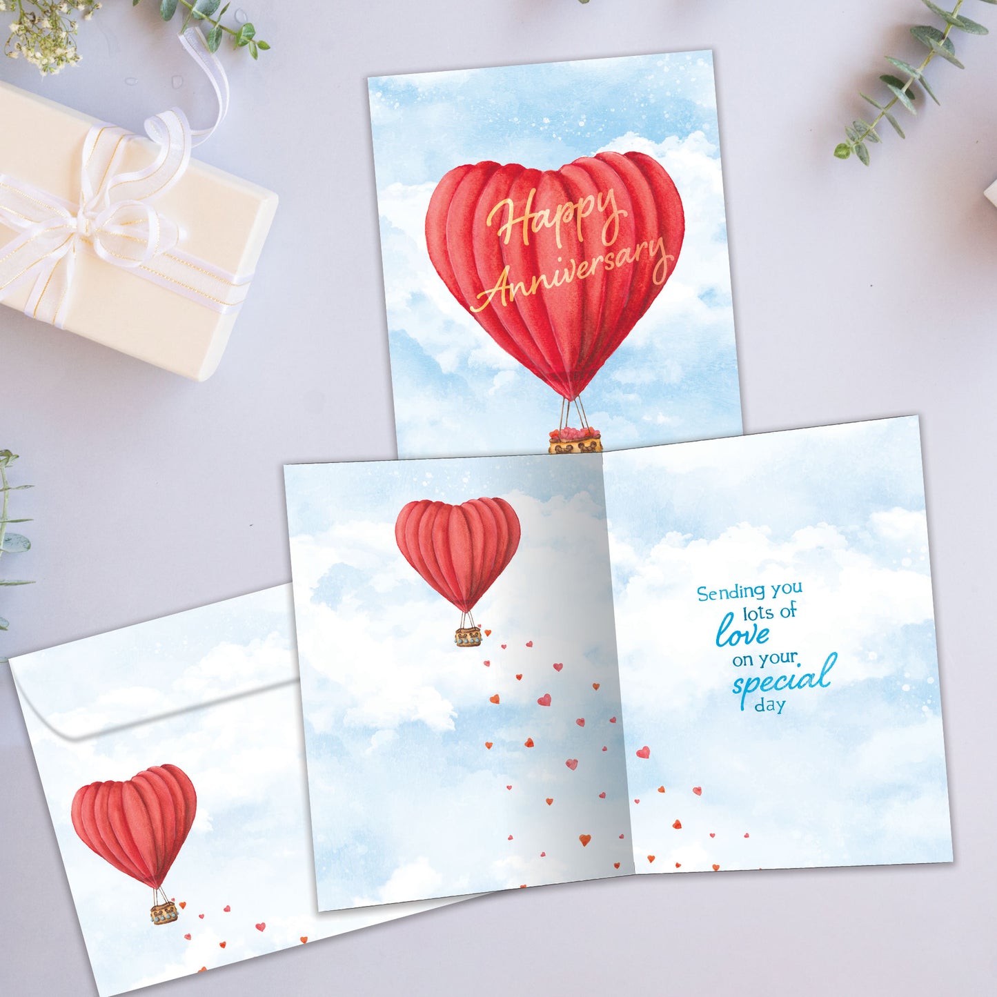 Front and inside view of an Anniversary greeting card showcasing a heart-shaped hot air balloon with the words "Happy Anniversary," with a matching envelope.