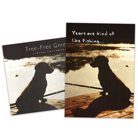 Front view of a Birthday greeting card featuring a dog fishing on a dock with a message about years being like fishing, with a matching envelope.