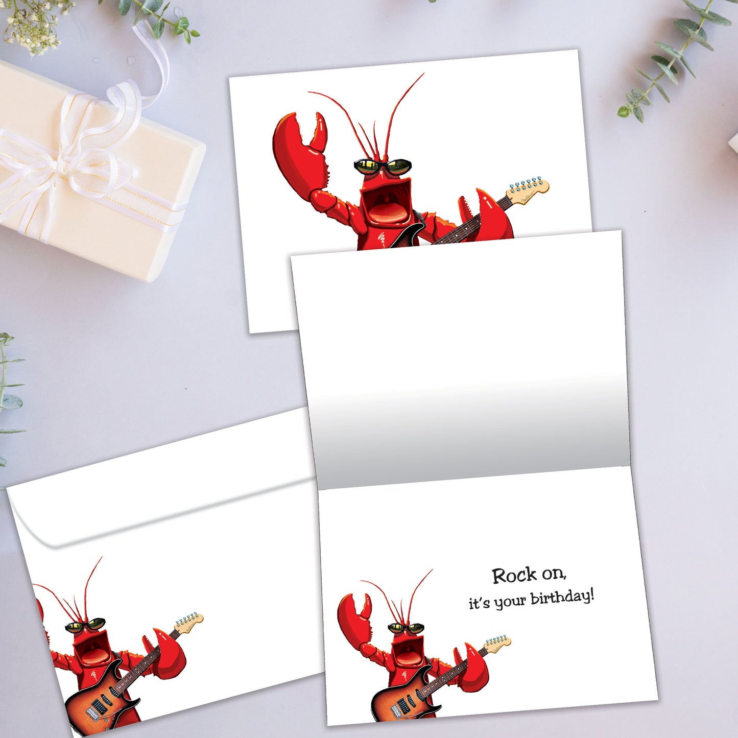 Front and inside view of a Birthday greeting card showcasing a lobster strumming a guitar, with a matching envelope.