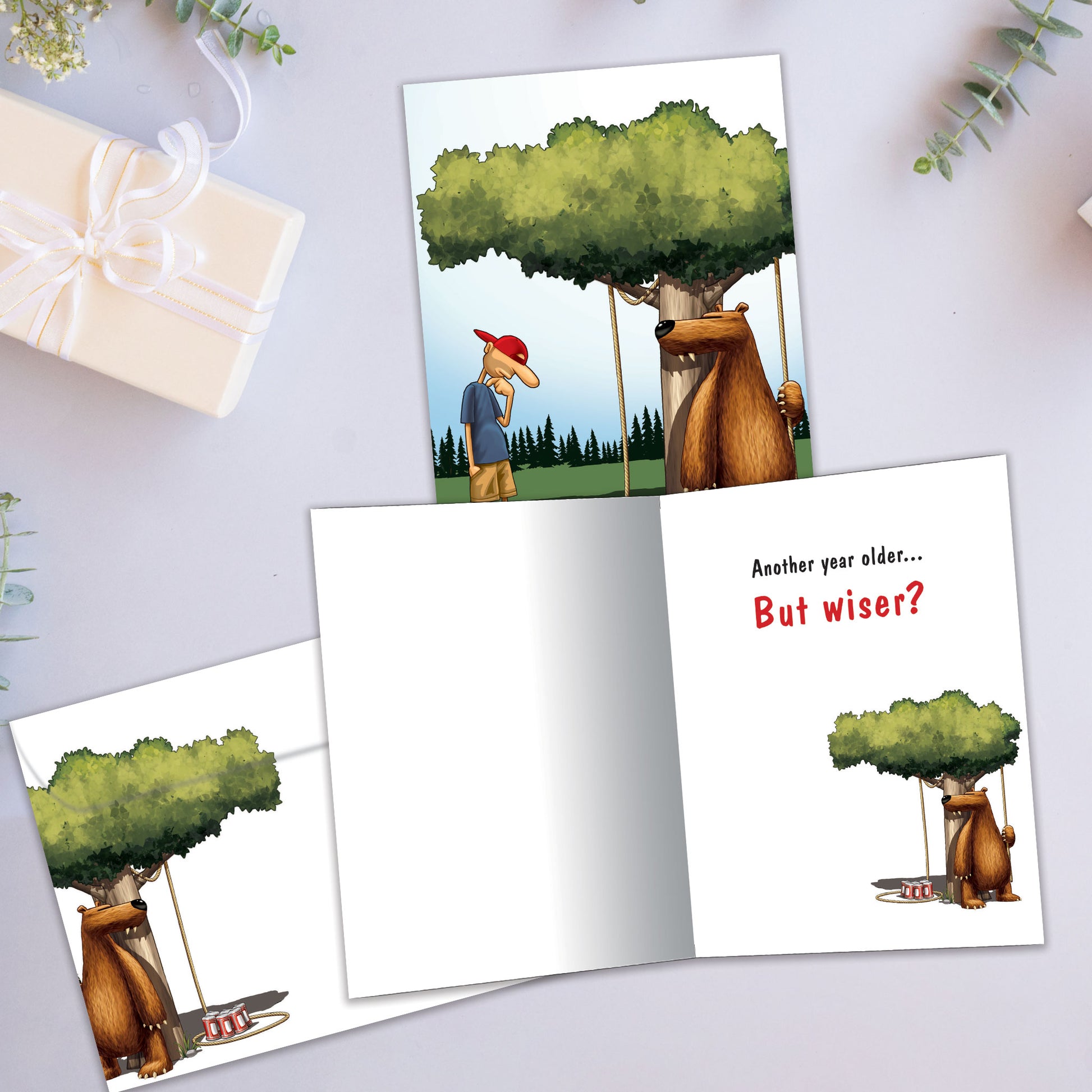Front and inside view of a Birthday greeting card showcasing a bear preparing a trap for a man, with a matching envelope.