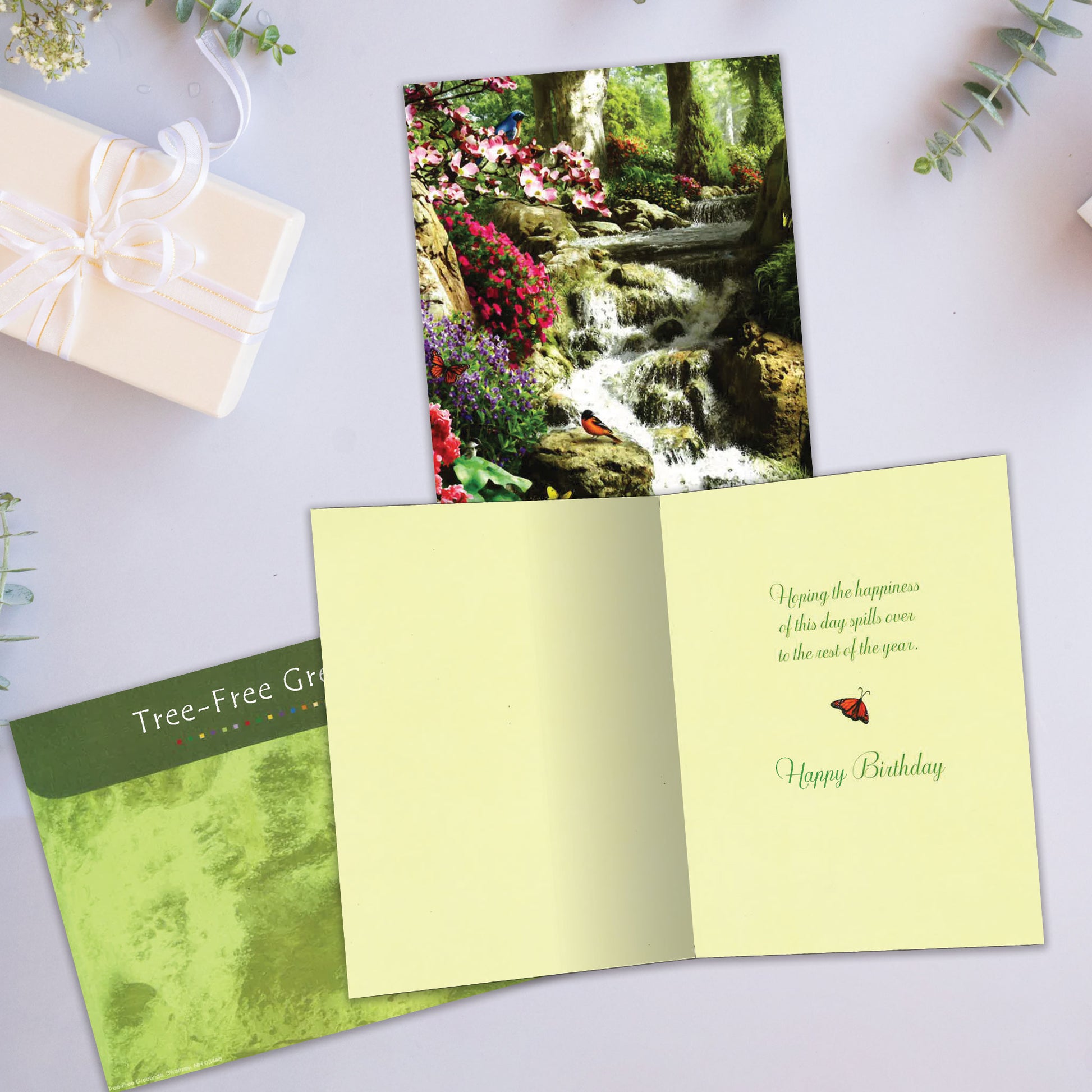 Front and inside view of a Birthday greeting card showcasing a serene forest and waterfall scene with flowers and birds, with a matching envelope.