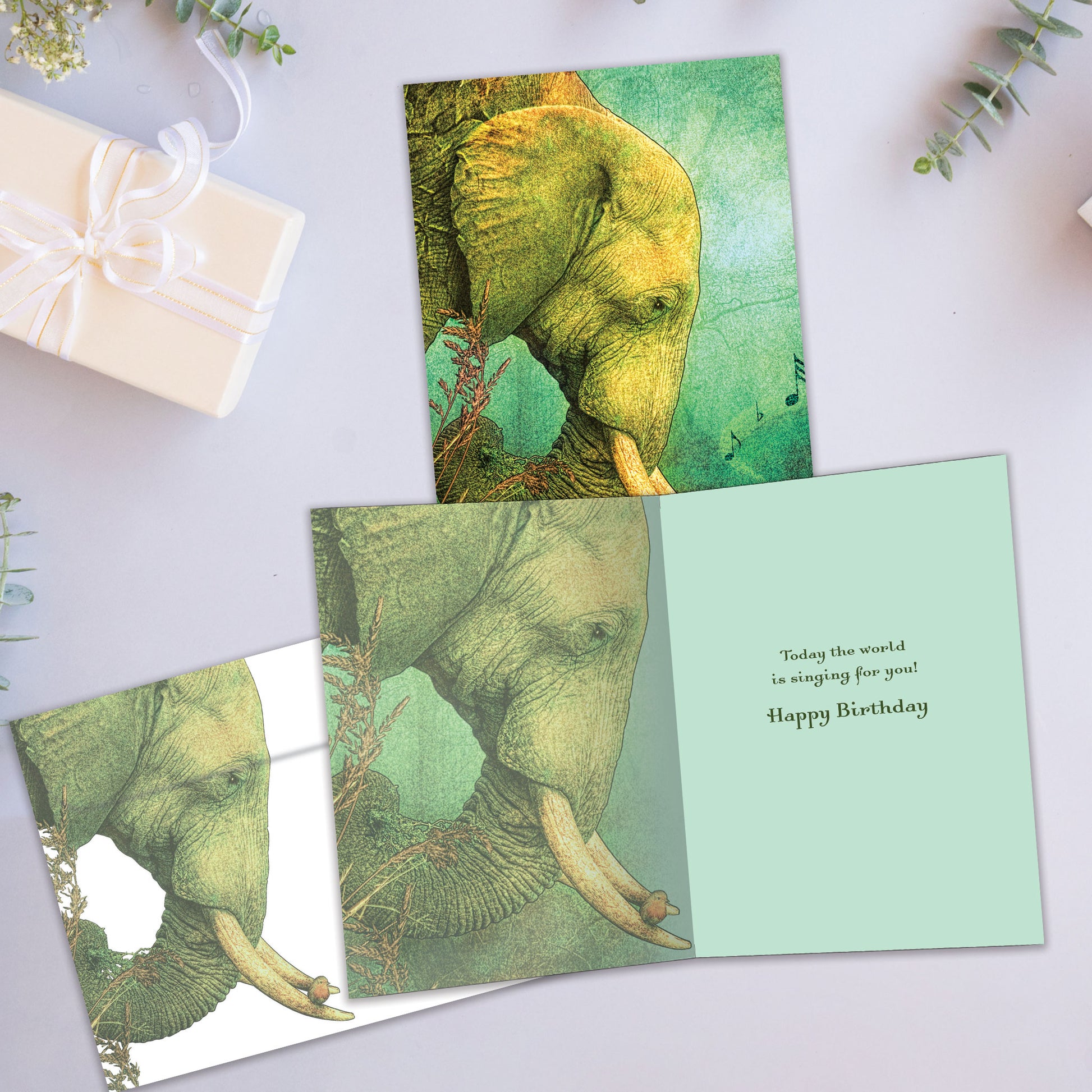 Front and inside view of a Birthday greeting card showcasing an elephant with musical notes against a light green background, with a matching envelope.