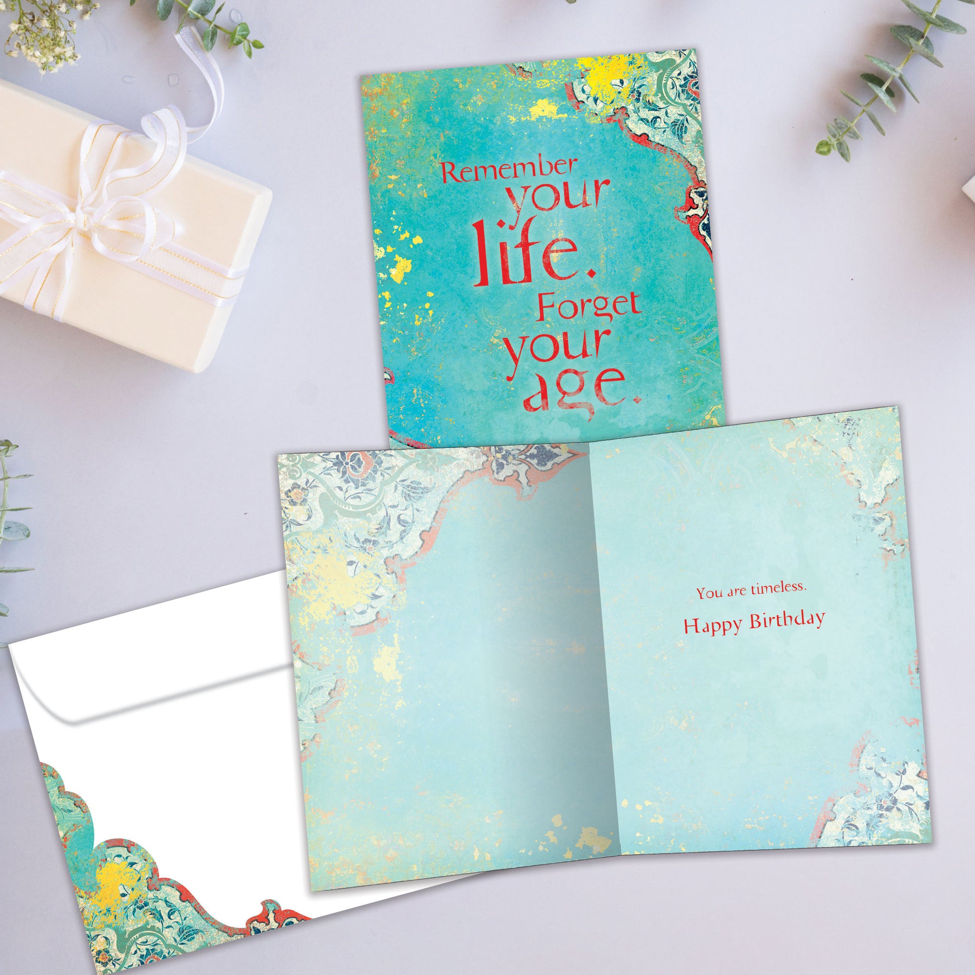 Front and inside view of a Birthday greeting card showcasing a message about life and aging on an artistic blue background, with a matching envelope.