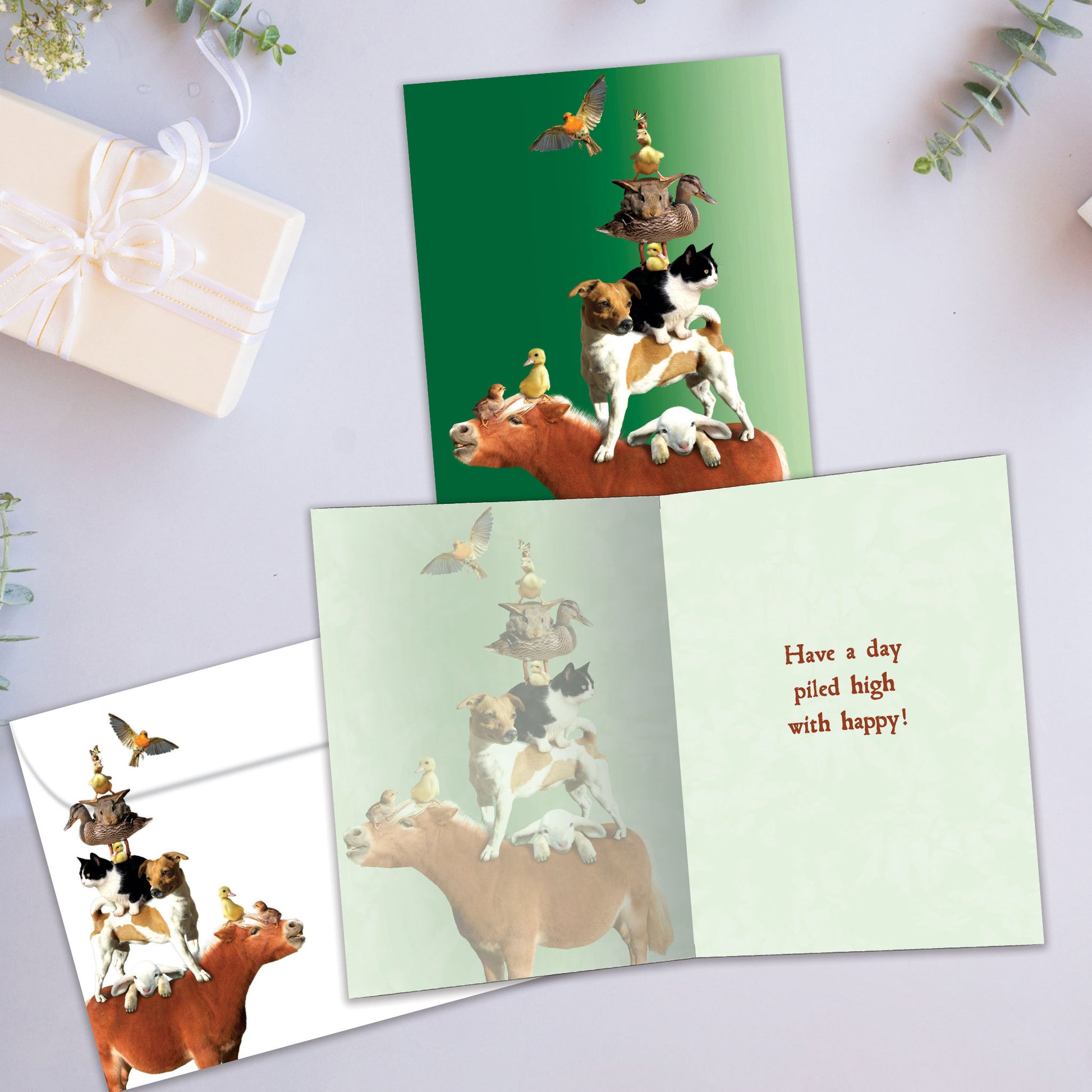 Front and inside view of a Birthday greeting card showcasing various animals piled on a mule with a green background, with a matching envelope.