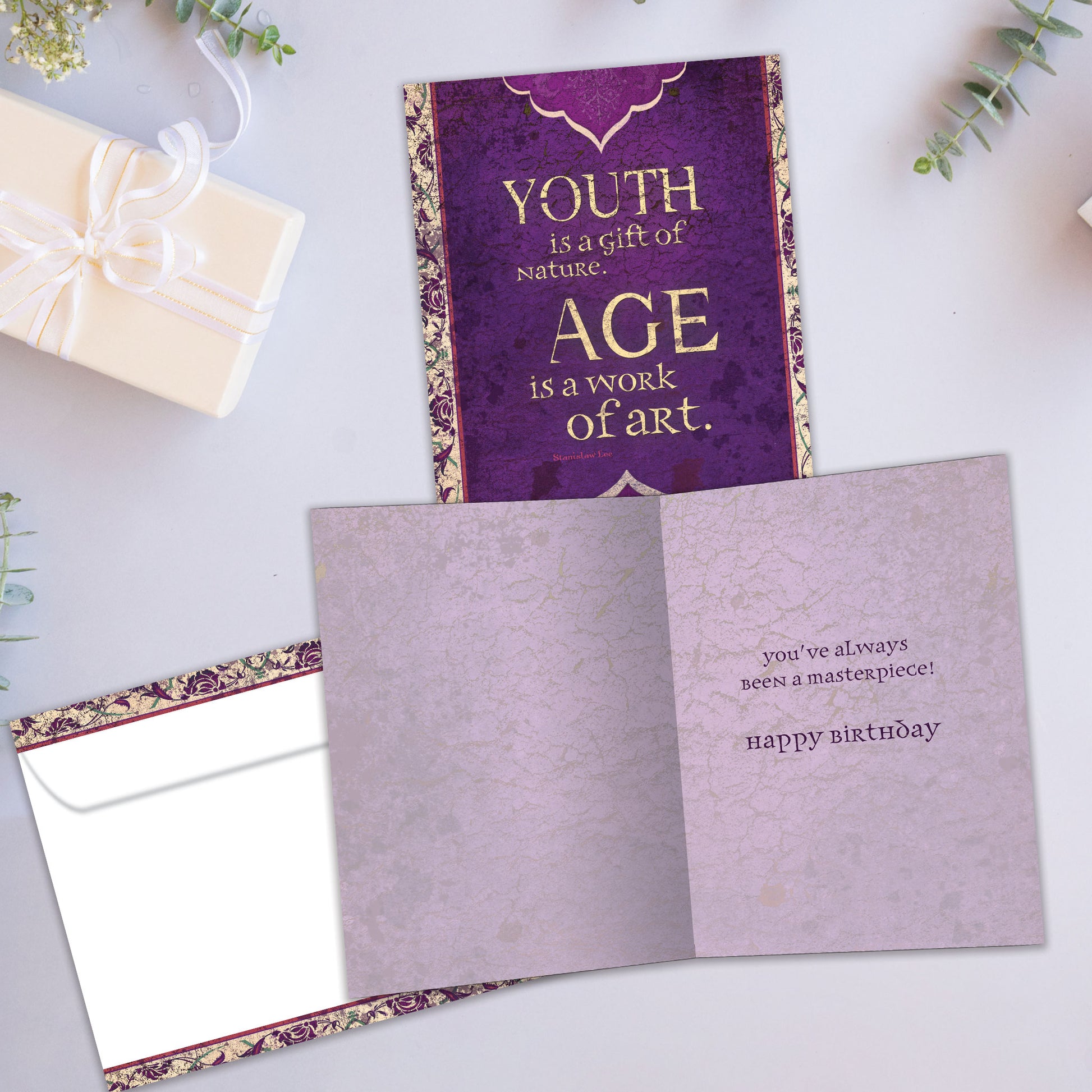 Front and inside view of a Birthday greeting card showcasing a message about age and art on a purple artistic background, with a matching envelope.