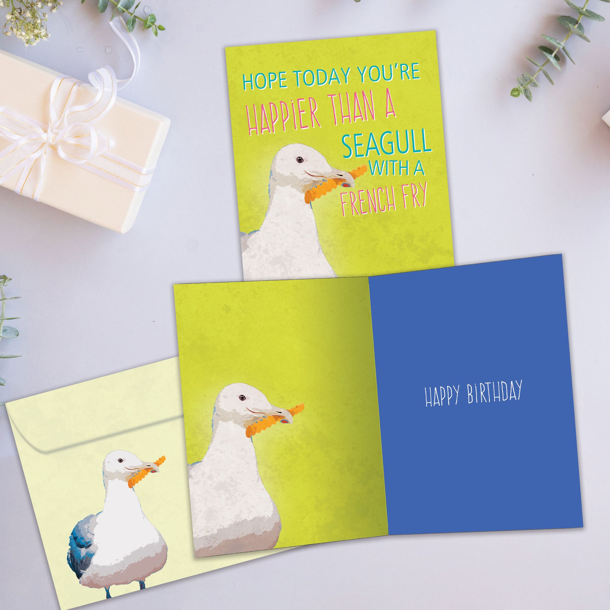 Front and inside view of a Birthday greeting card showcasing a seagull illustration holding a french fry, with a matching envelope.