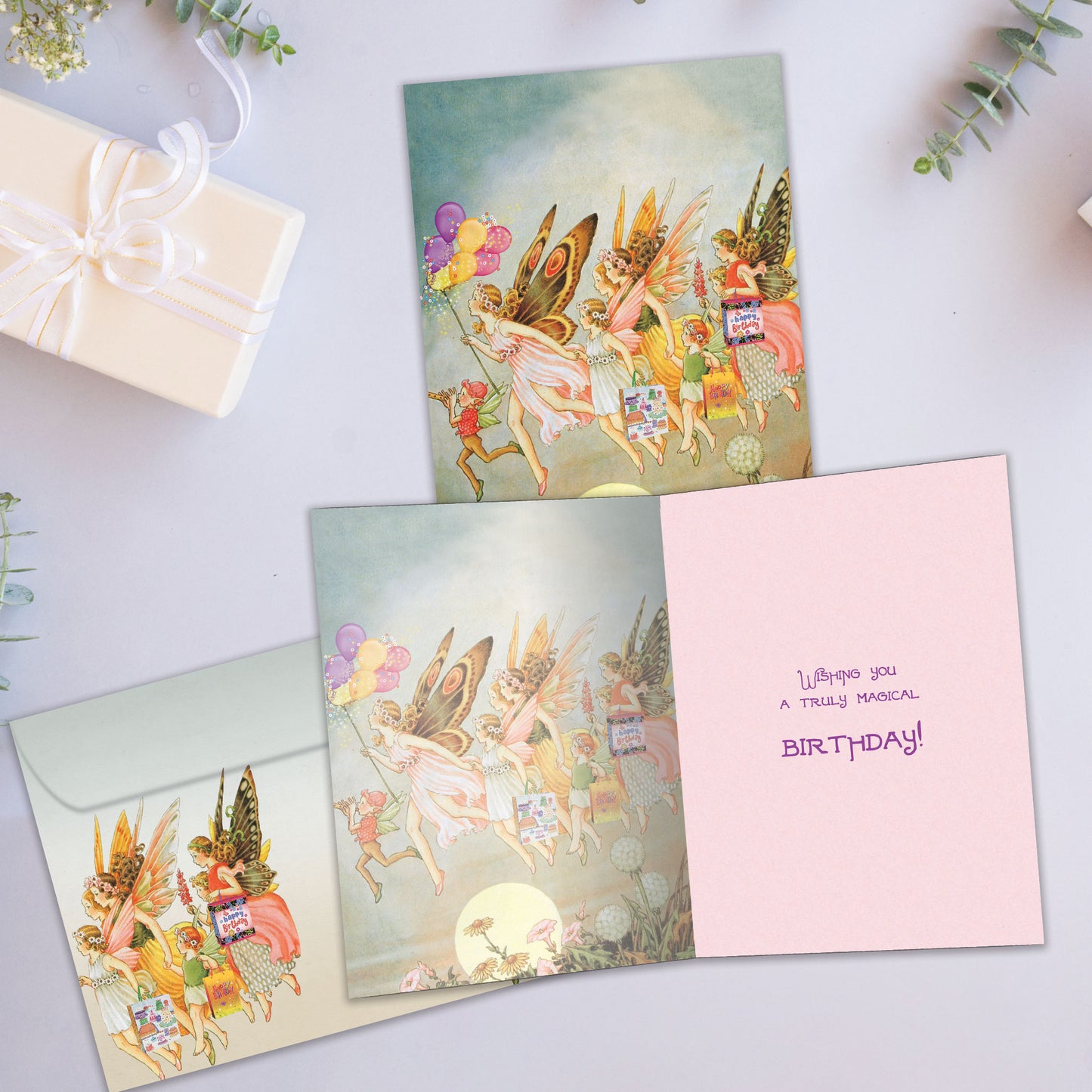 Front and inside view of a Birthday greeting card showcasing an illustration of fairies flying, with a matching envelope.