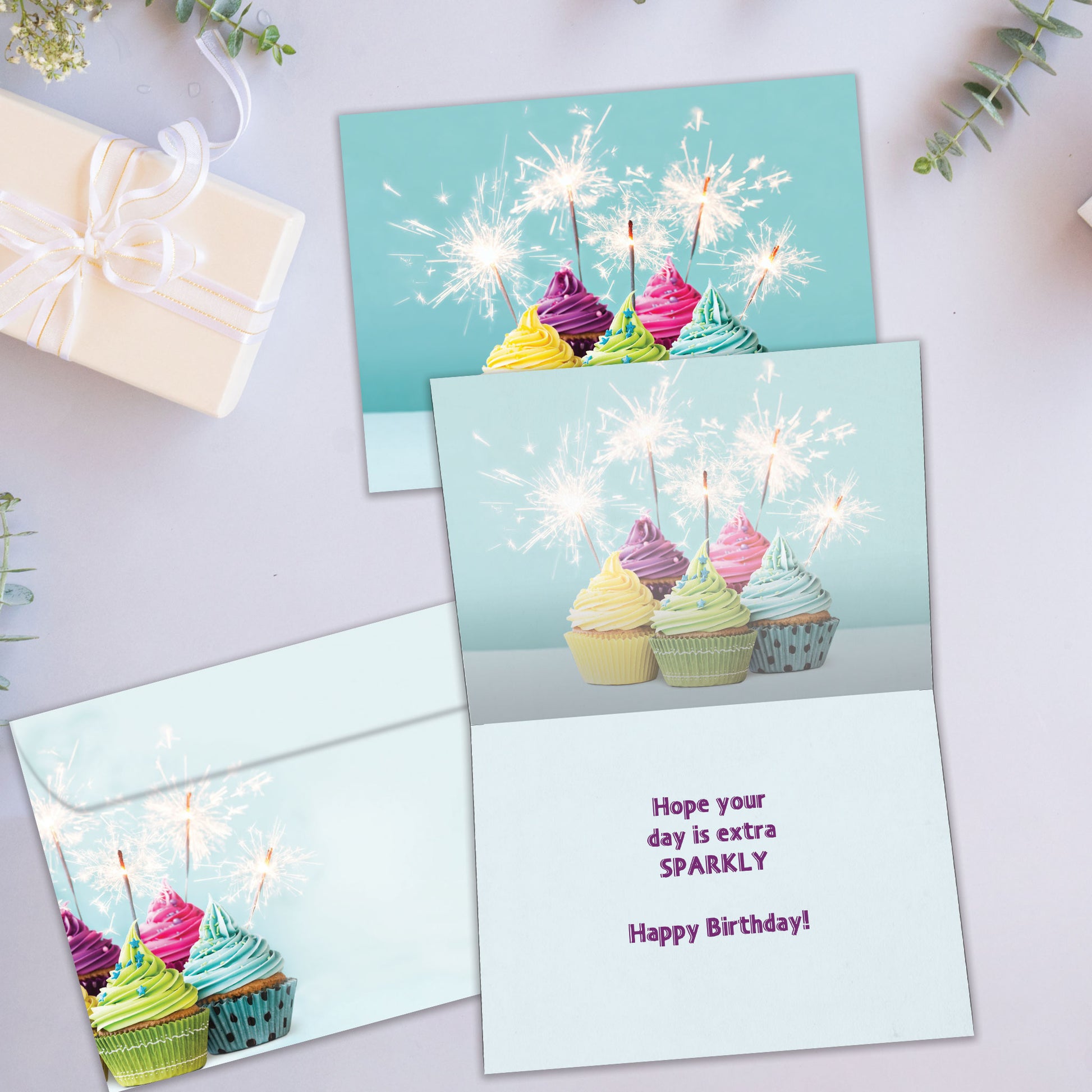 Front and inside view of a Birthday greeting card showcasing an image of cupcakes with lit sparkles, with a matching envelope.