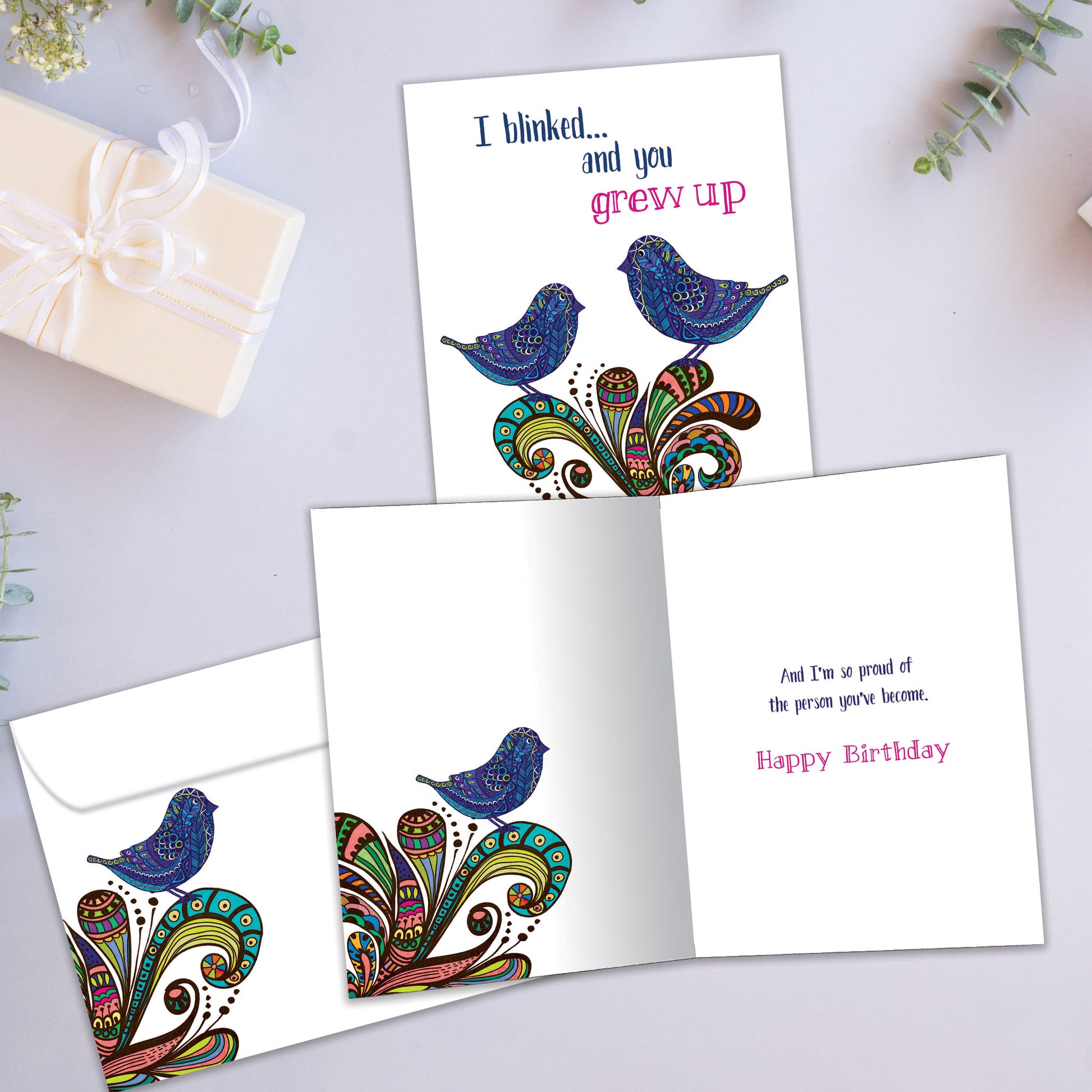 Front and inside view of a Birthday greeting card showcasing artistic birds with the message "I blinked…and you grew up," with a matching envelope.