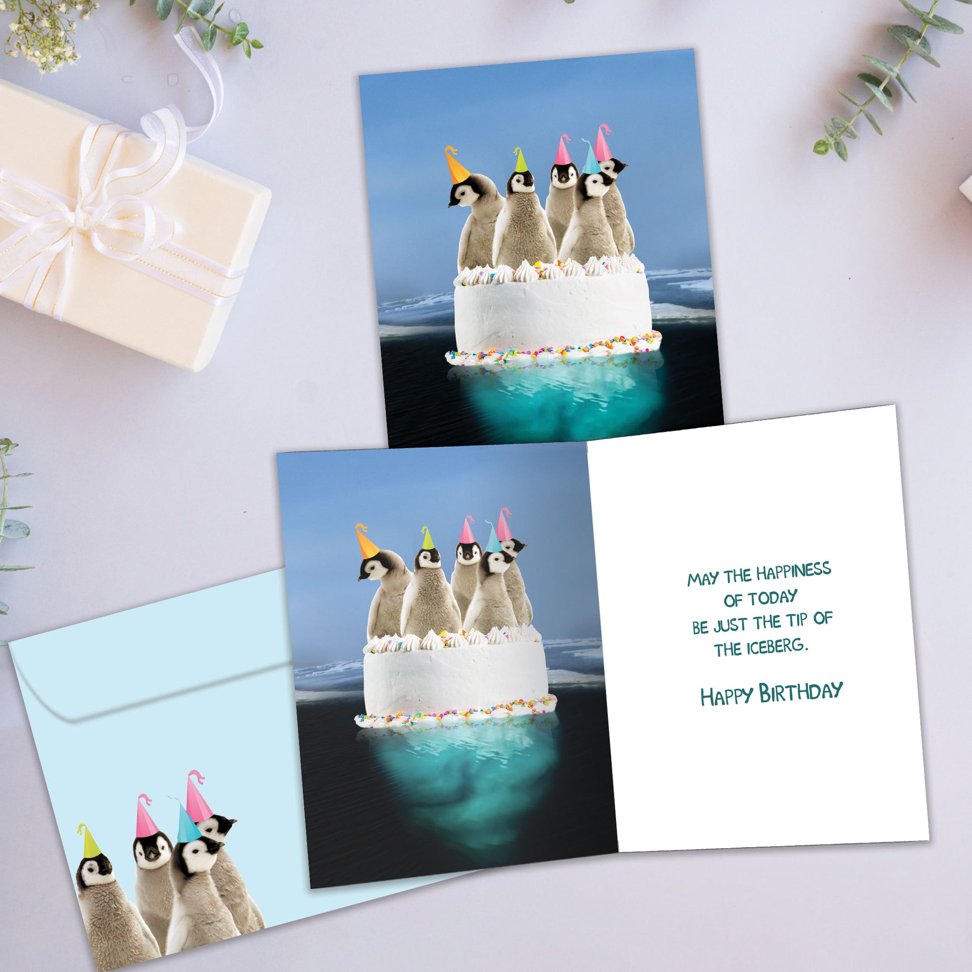 Front and inside view of a Birthday greeting card showcasing penguins on a cake illustration, with a matching envelope.
