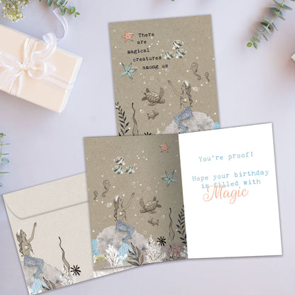 Front and inside view of a Birthday greeting card showcasing a mermaid and sea creatures in a magical setting, with a matching envelope.